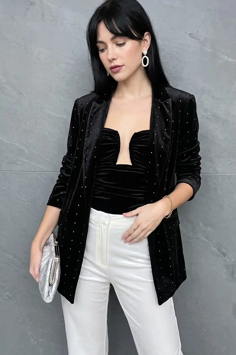 Woman in black crystal embellished velvet blazer with white trousers and black velvet bodysuit