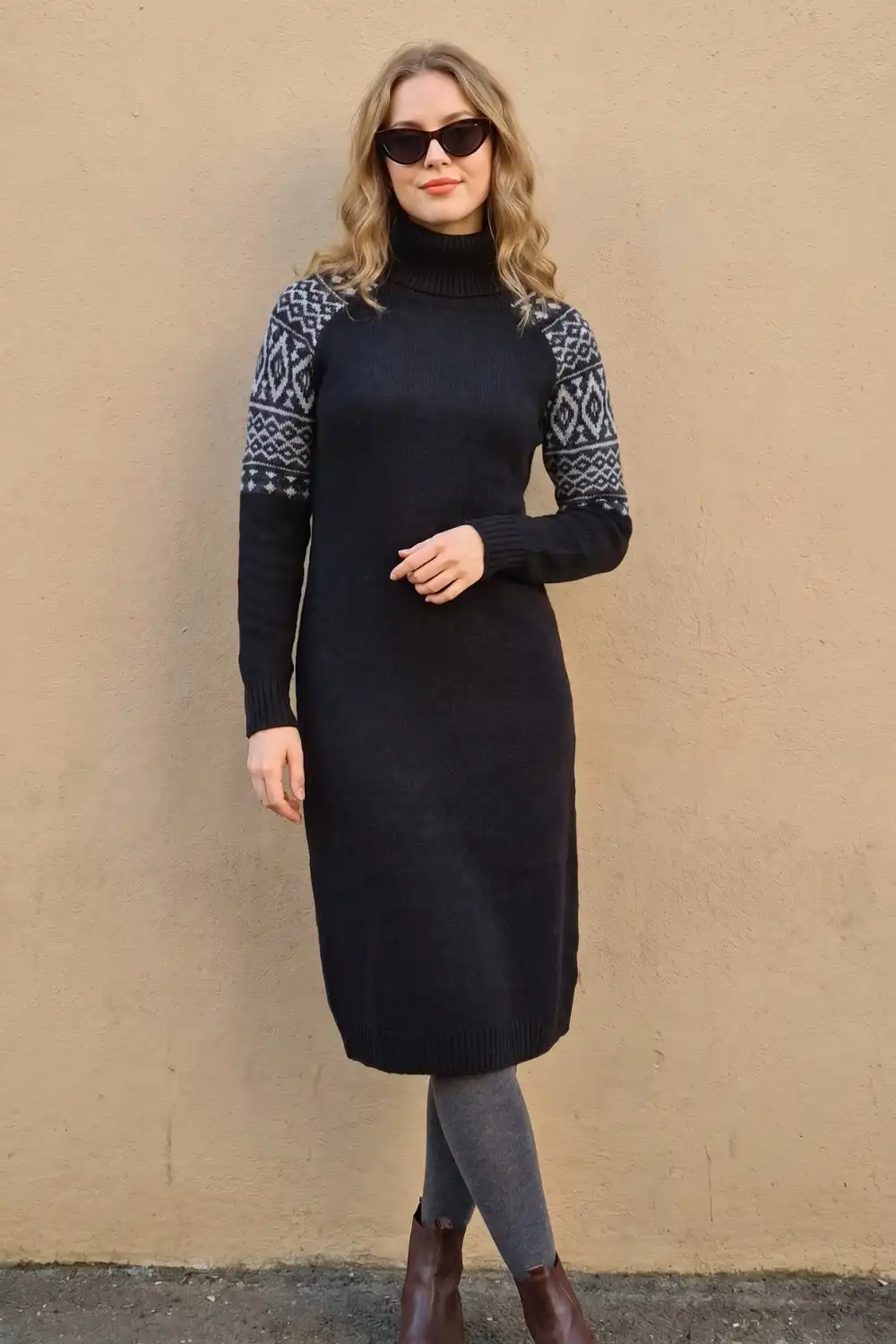 Woman in black grey fair isle turtleneck knit midi sweater dress with grey leggings and brown boots