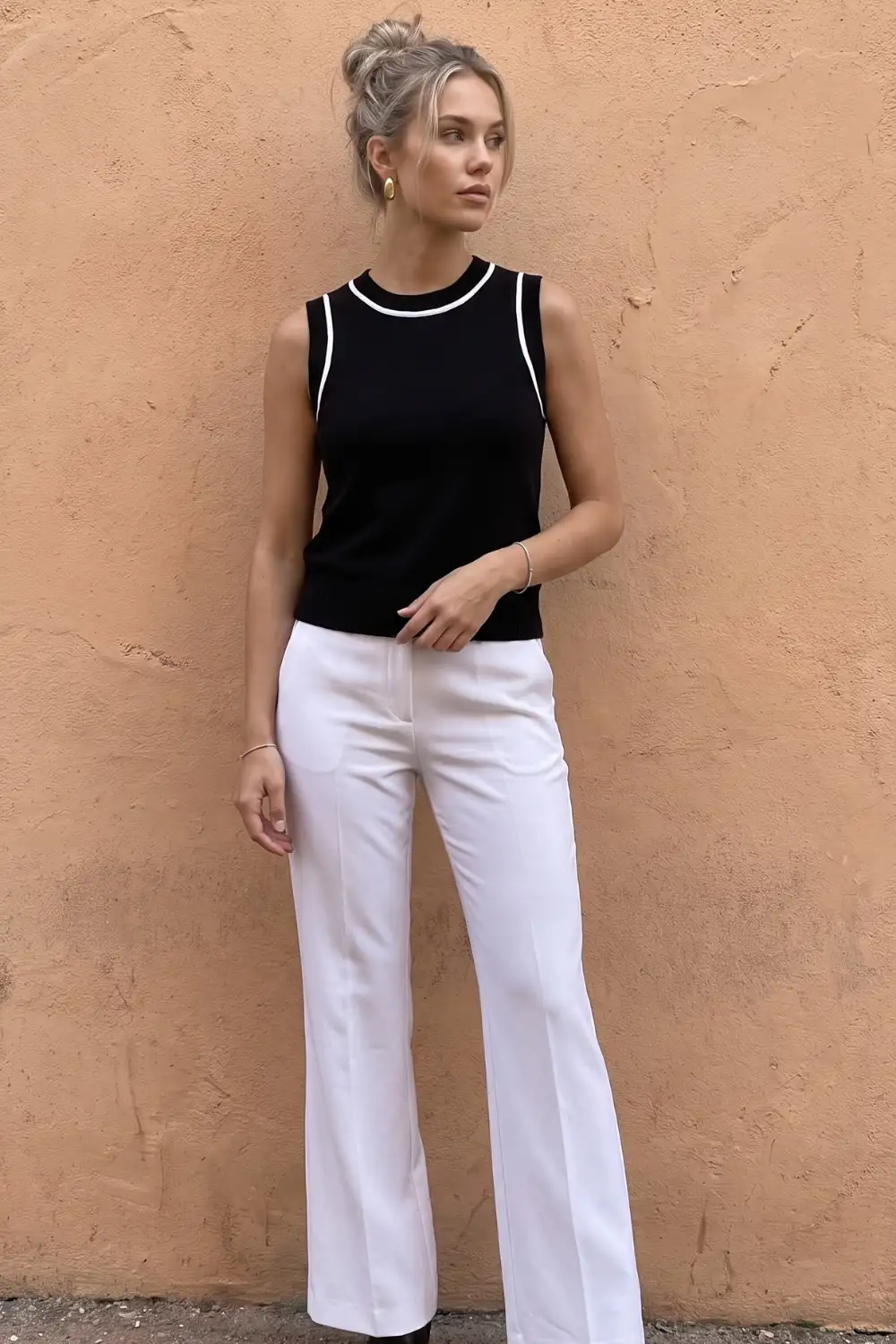 Woman in black sleeveless crew neck knit top with white trim and white wide leg trousers