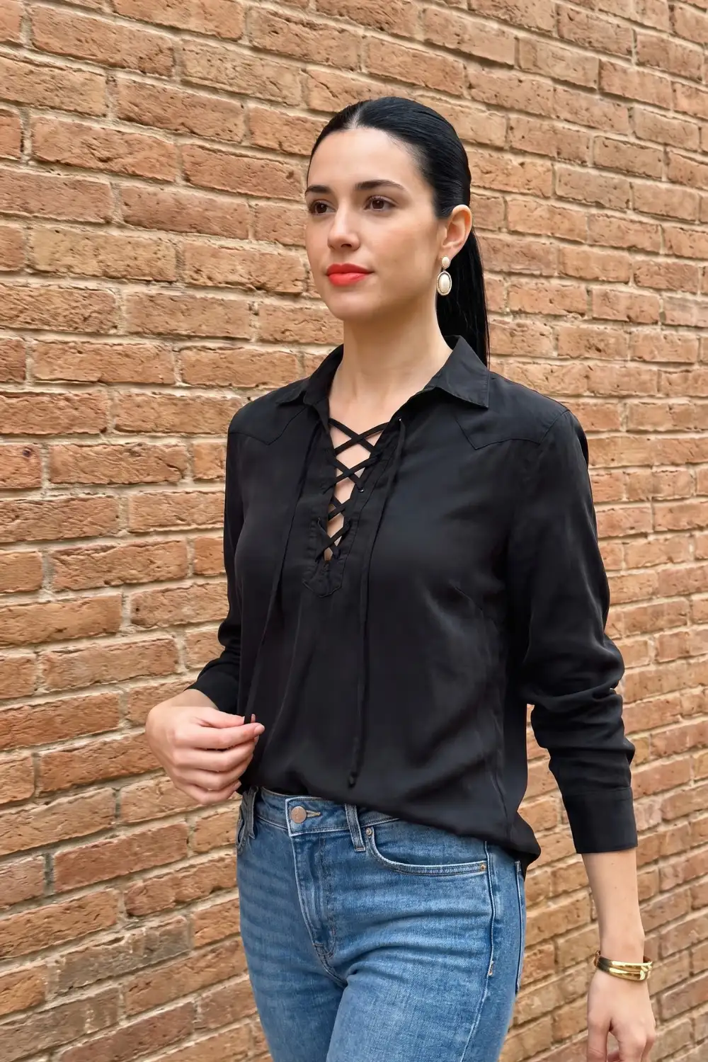 Woman in black satin lace-up collar long sleeve shirt with blue jeans