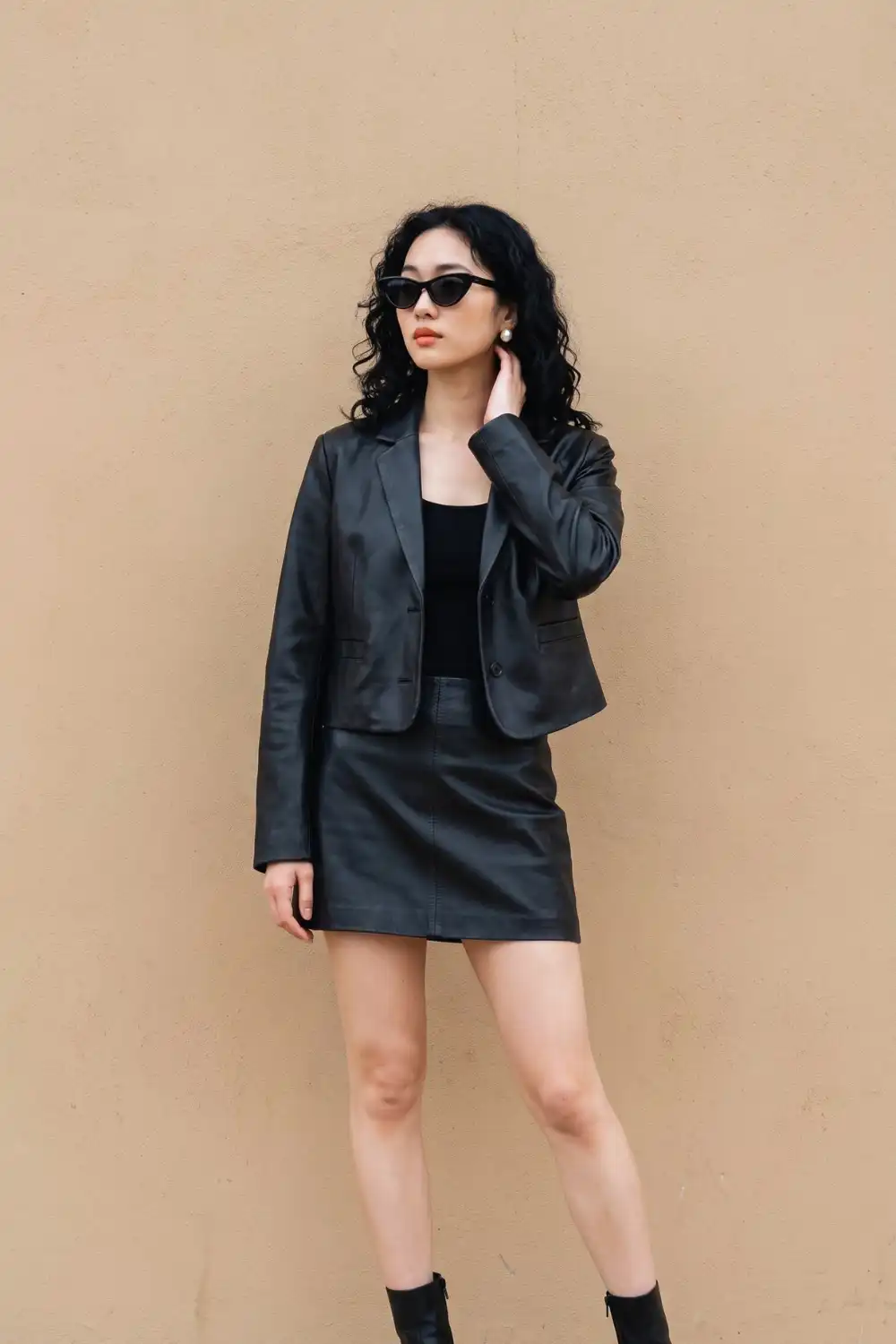 Woman in black leather blazer jacket with black tank top and black leather mini skirt