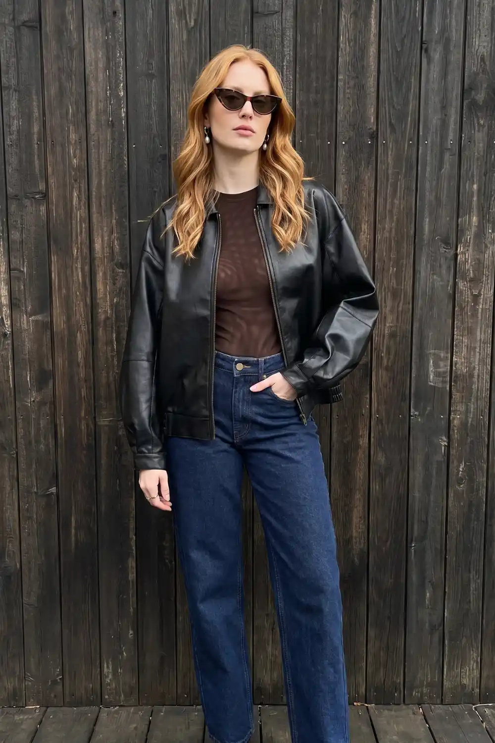 Woman wearing black oversized leather bomber jacket with brown sheer mesh top