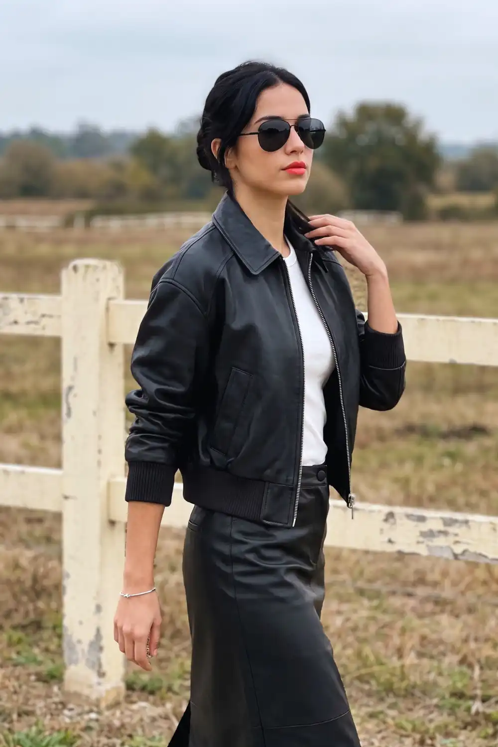 Woman in black leather zip-up bomber jacket with white tee and black leather midi skirt