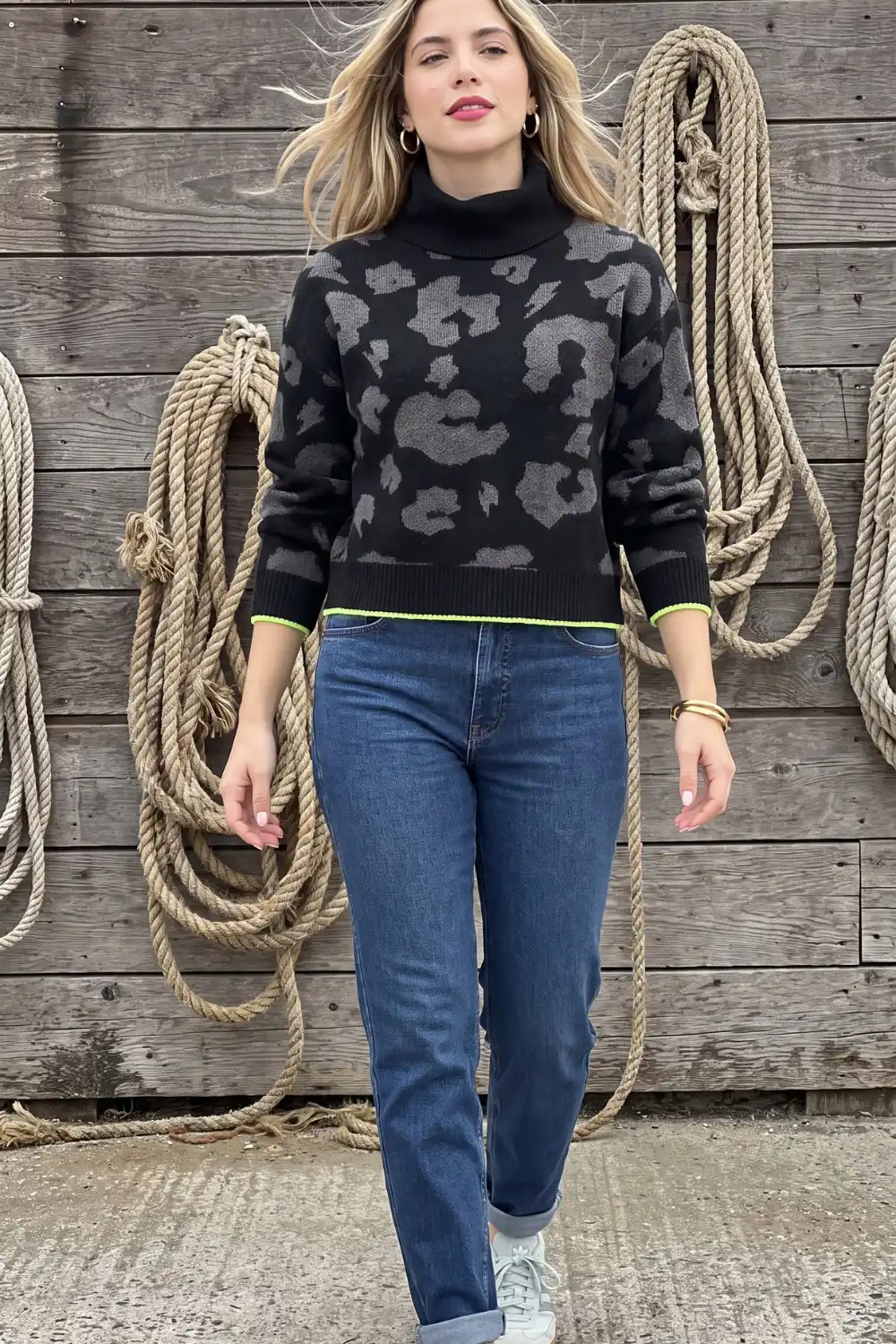 Woman in black grey leopard print turtleneck knit sweater with blue jeans