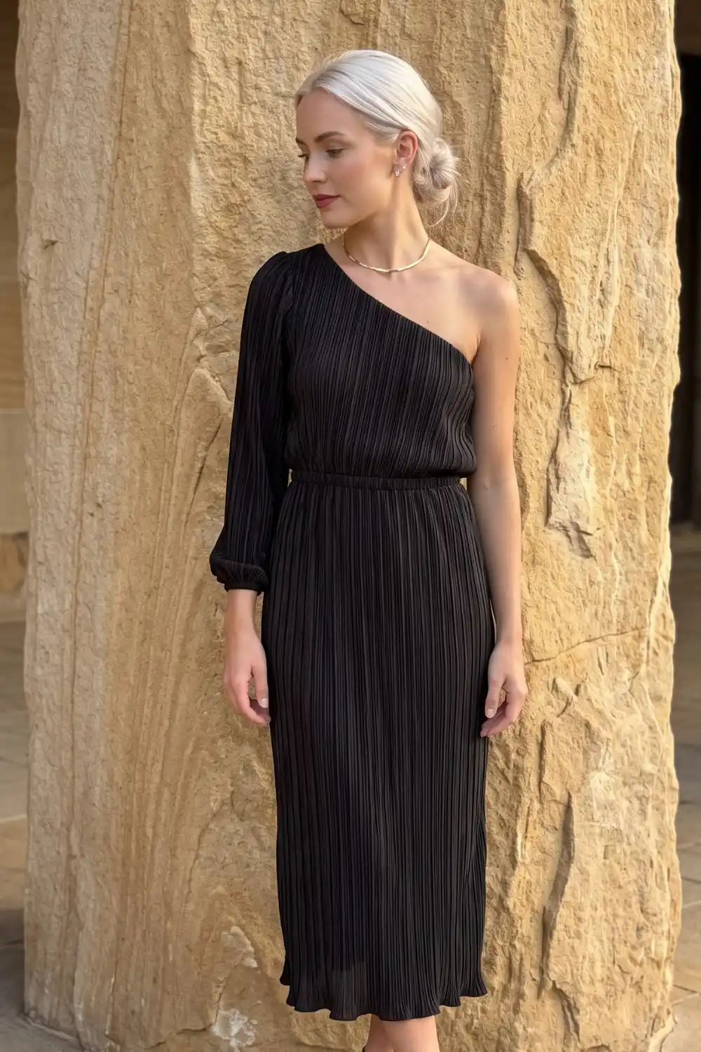 Woman wearing black one shoulder pleated midi dress