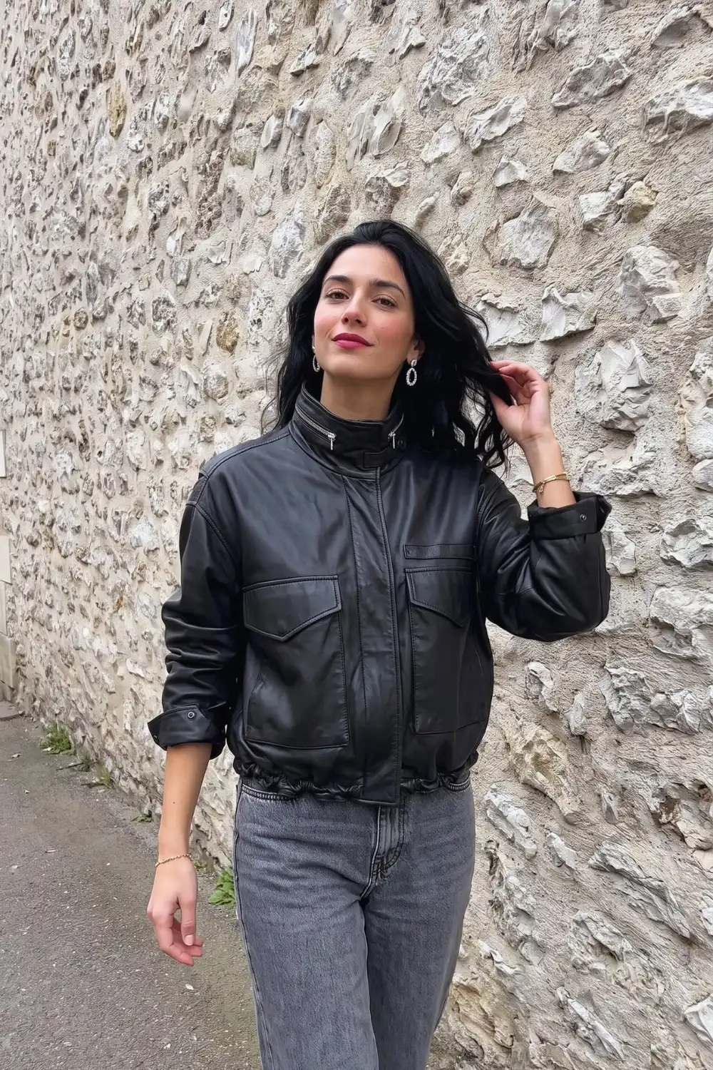 Woman in black oversized high-neck leather bomber jacket with grey wash wide leg jeans