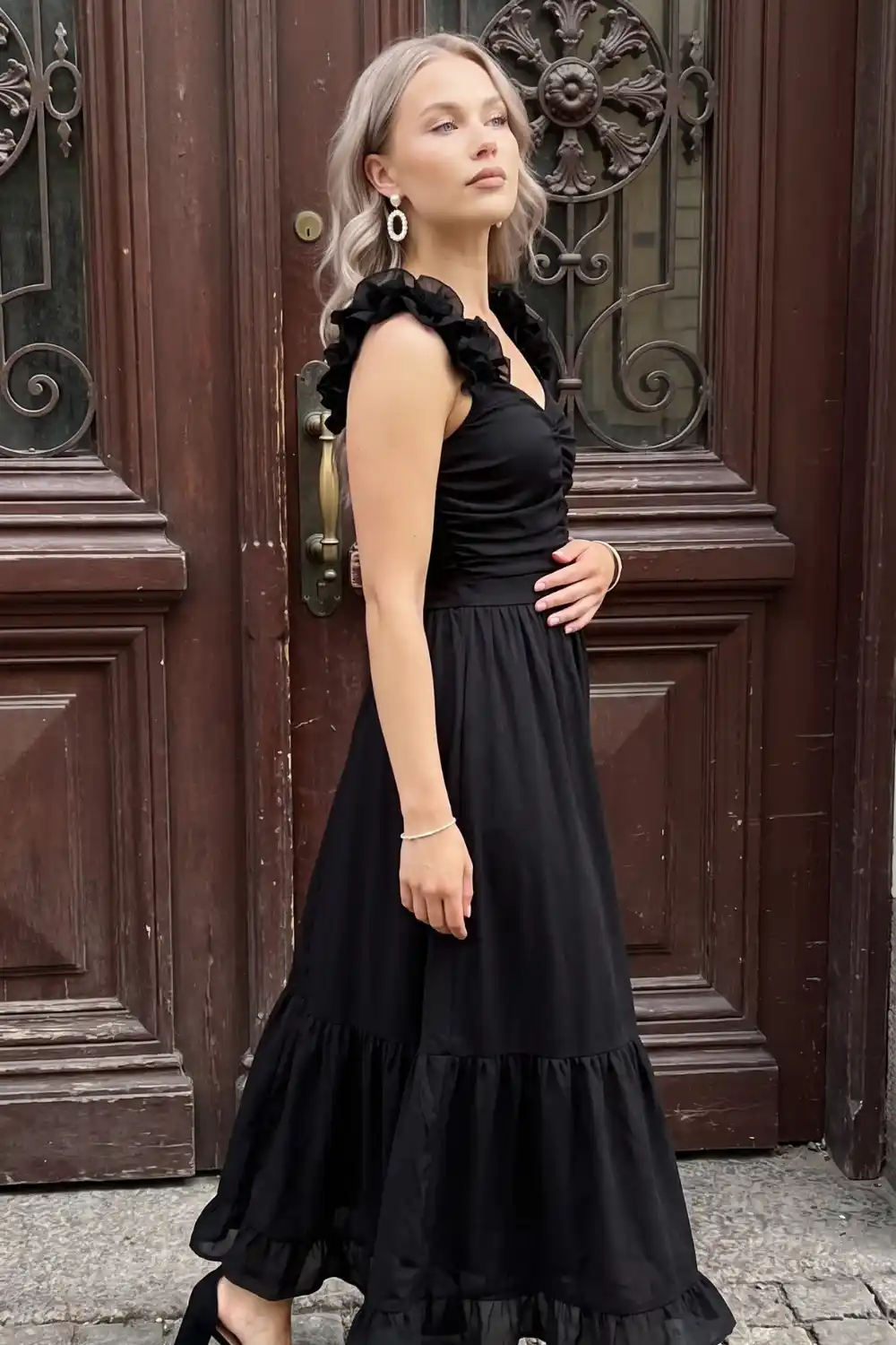 Woman in black ruffle strap v-neck tiered maxi dress