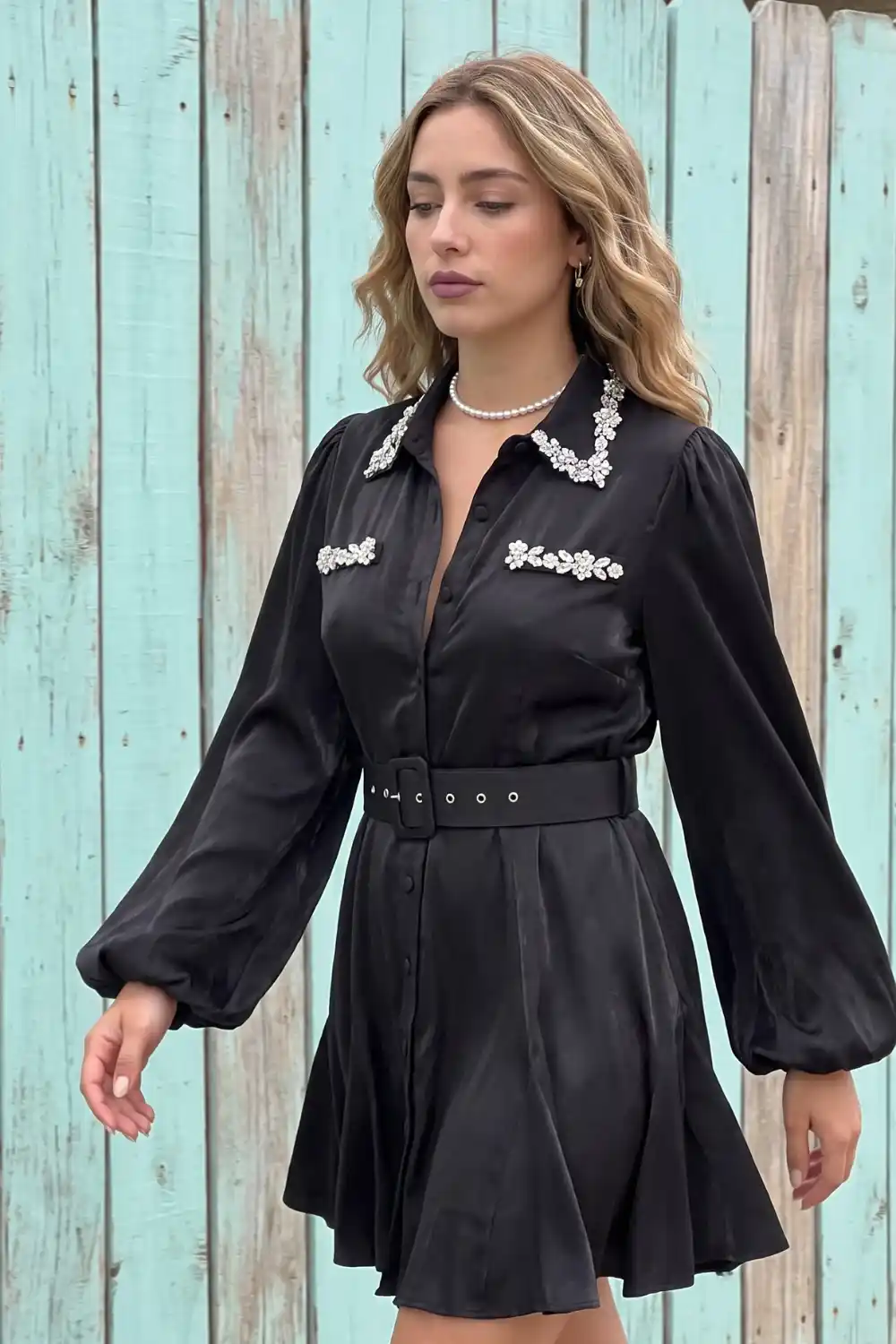 Woman wearing black satin balloon sleeve mini shirt dress with crystal collar detail