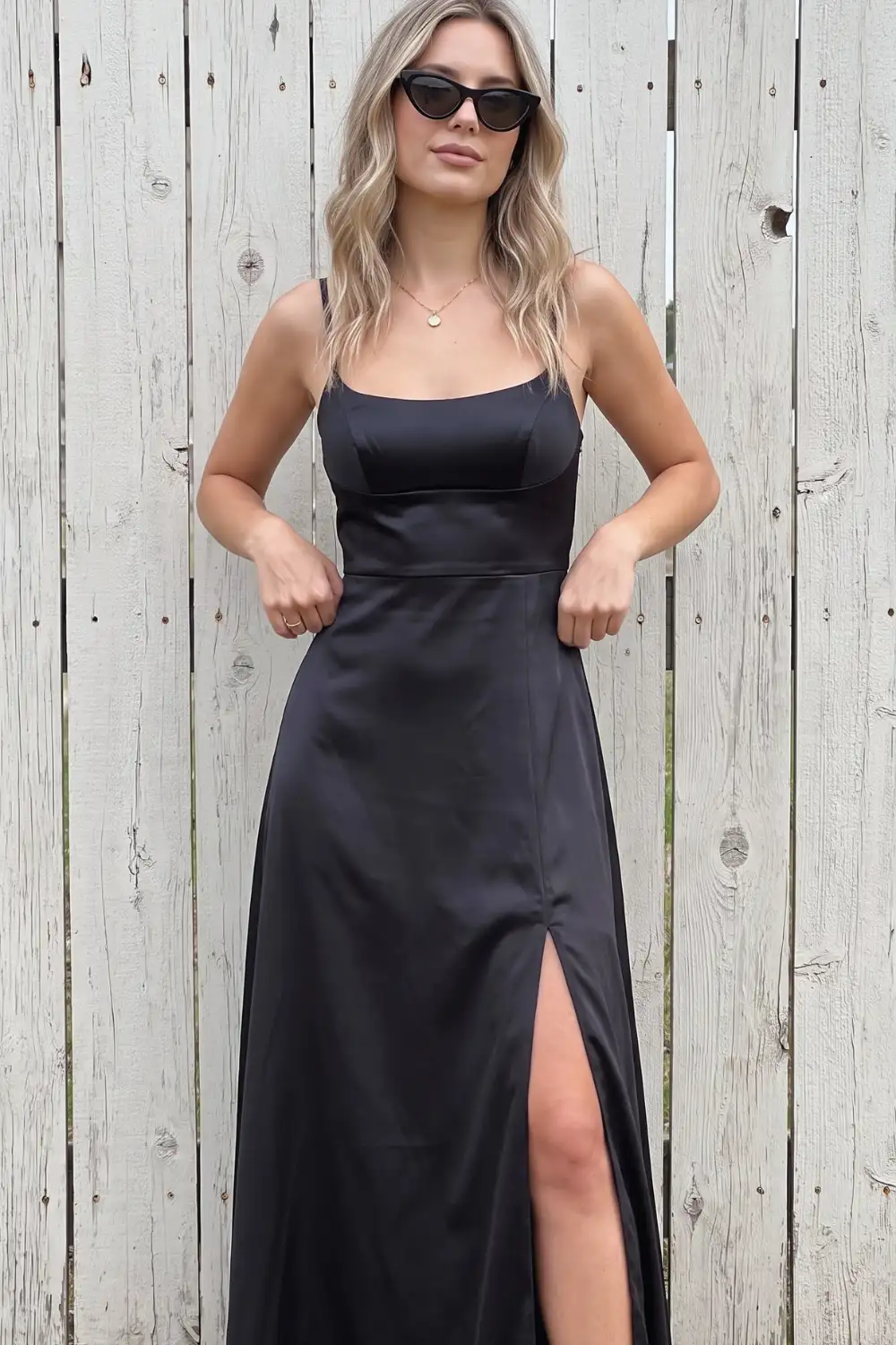 Woman in black satin square neck fitted slip maxi dress with side slit