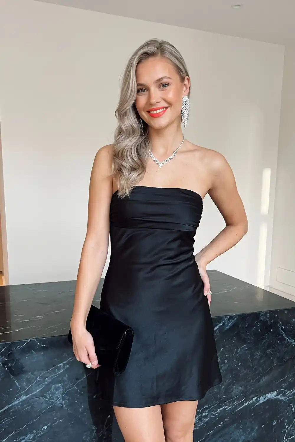 Woman wearing black satin strapless ruched bandeau mini dress