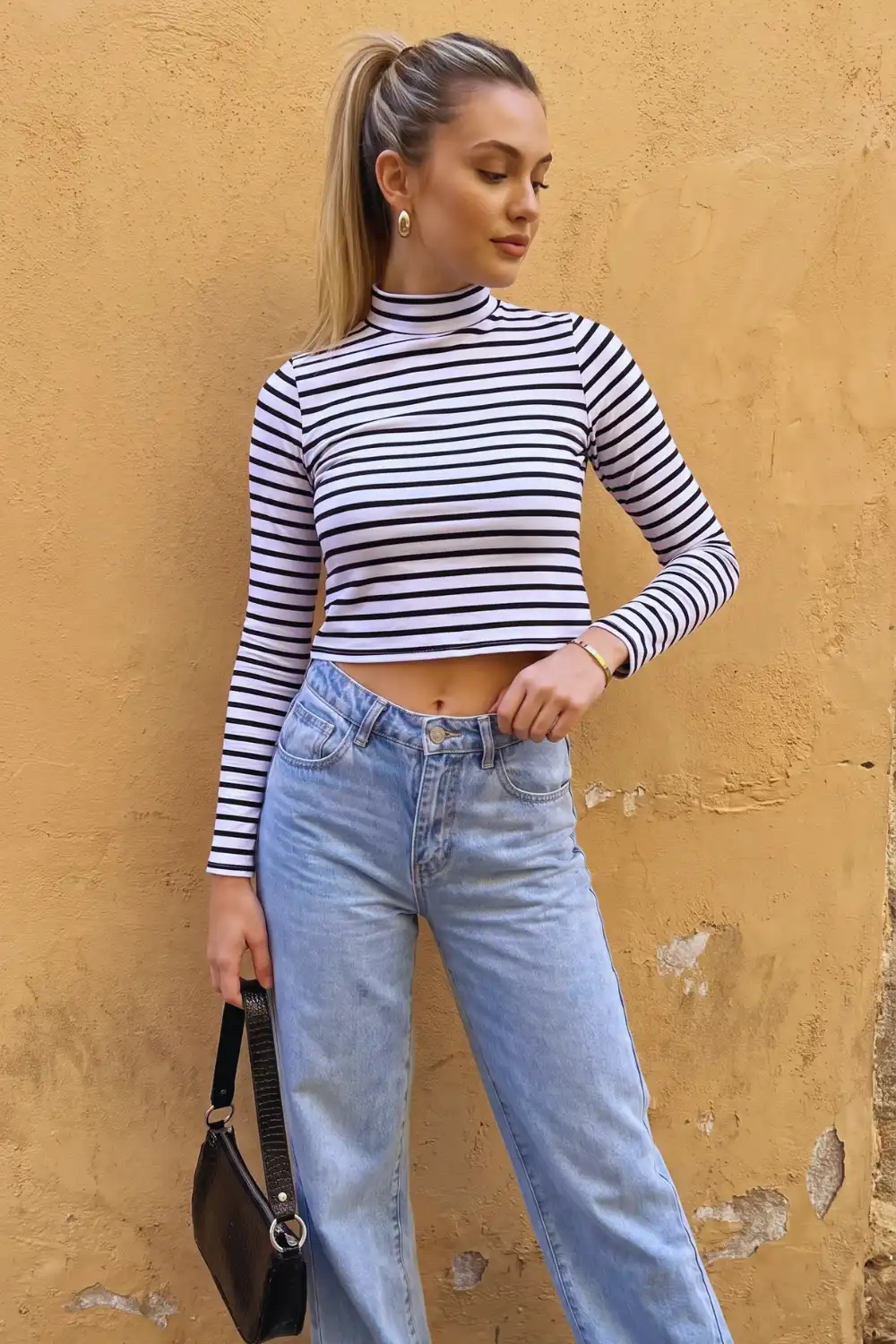 Woman in white black stripe cropped mock neck long sleeve top with light wash wide leg jeans