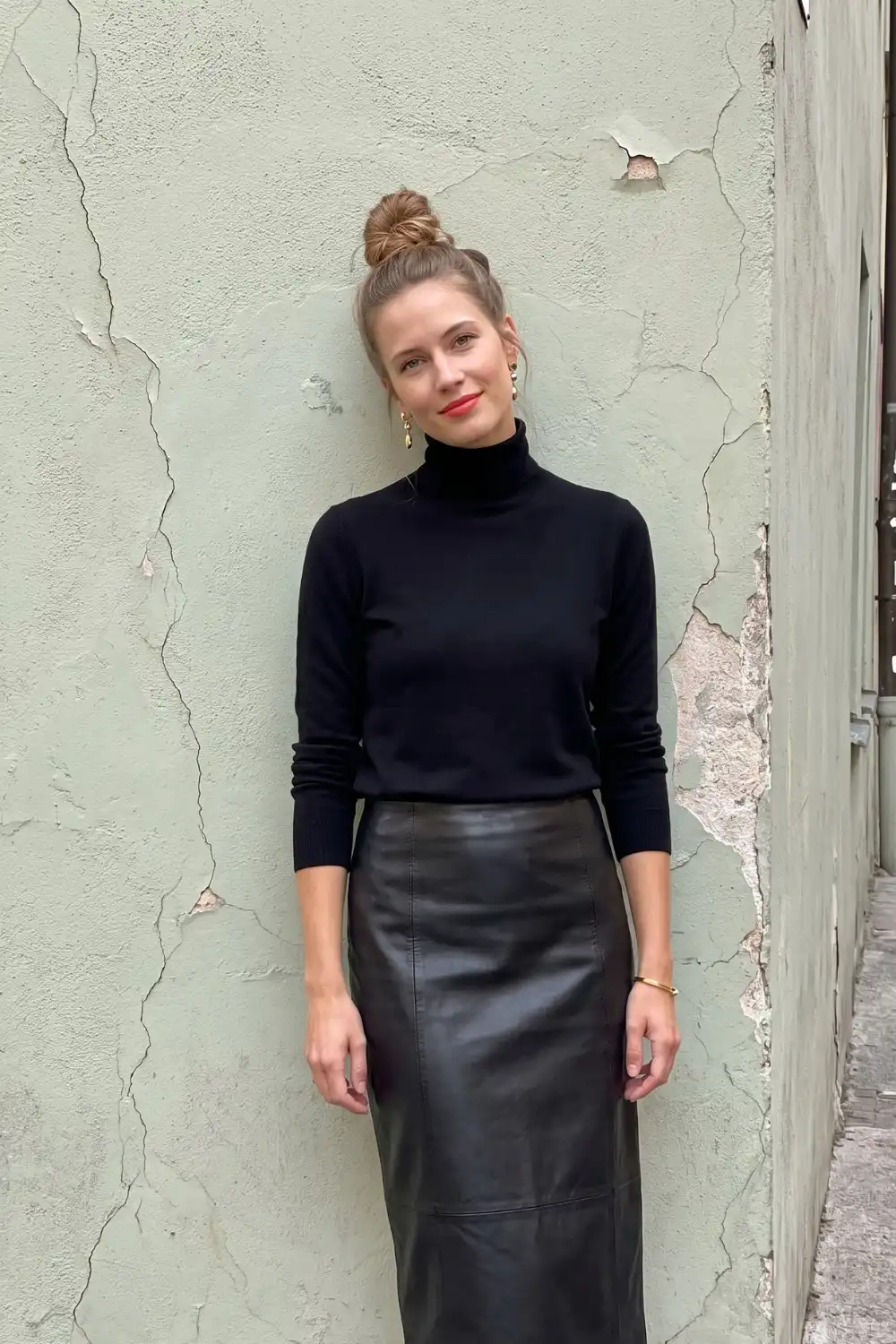 Woman in black fitted turtleneck knit top with black leather midi pencil skirt