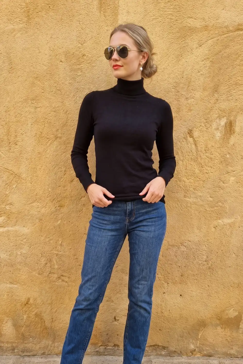 Woman in black fitted turtleneck top with blue straight leg jeans