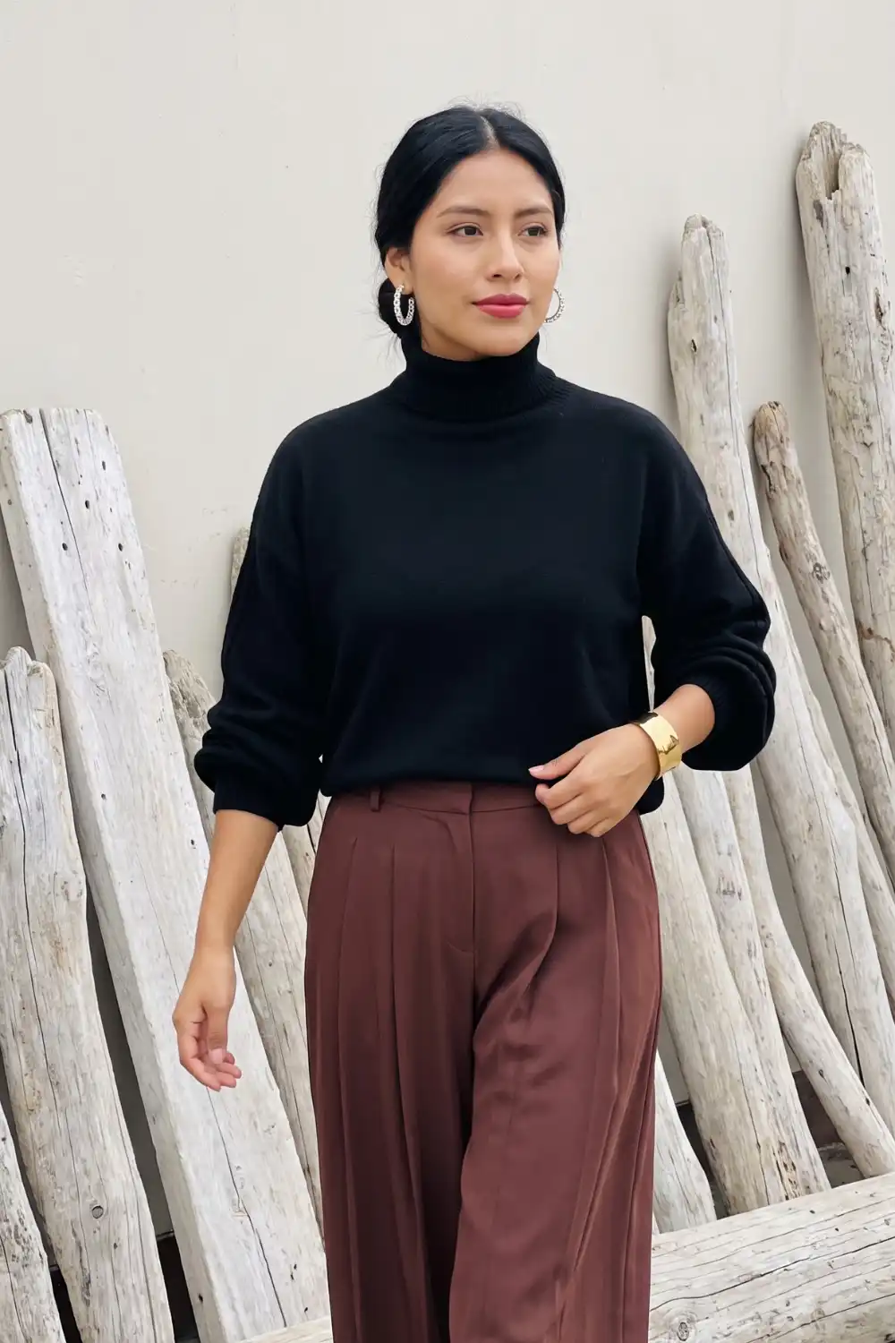 Woman in black oversized turtleneck sweater with chocolate brown wide leg pleated trousers