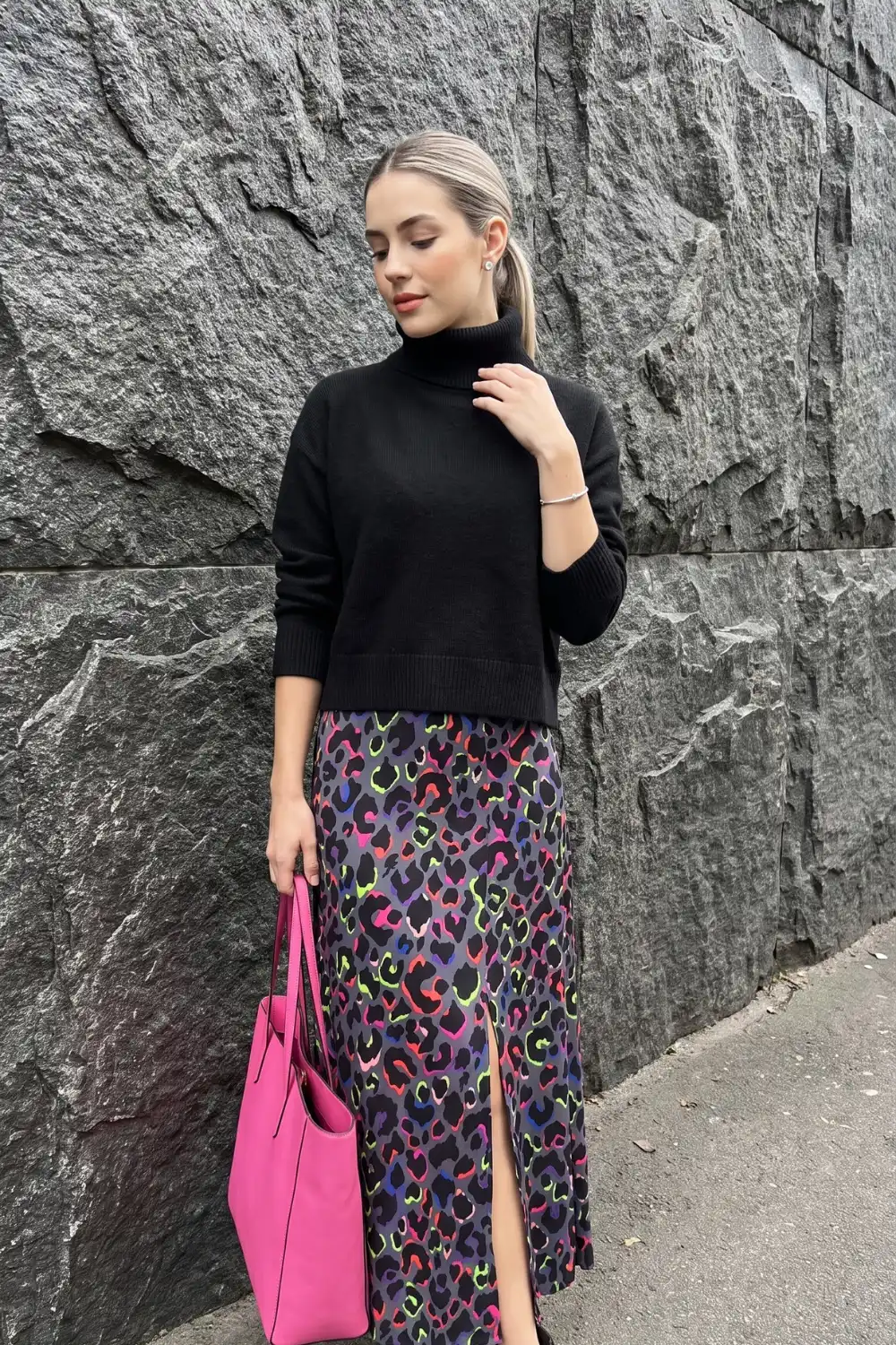 Woman in black cropped turtleneck with multicolour neon leopard print satin midi skirt