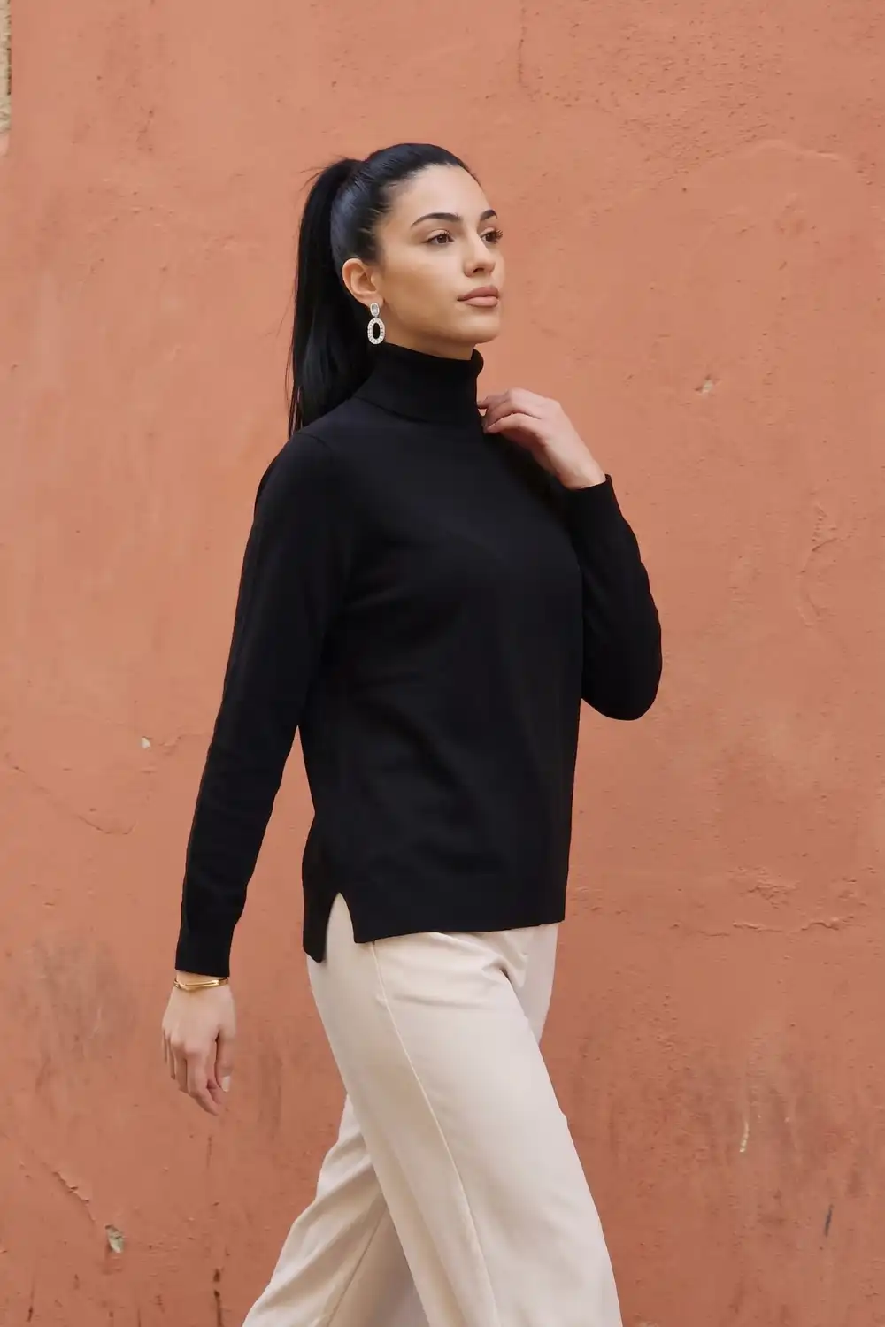 Woman in black oversized turtleneck knit sweater with cream wide leg trousers