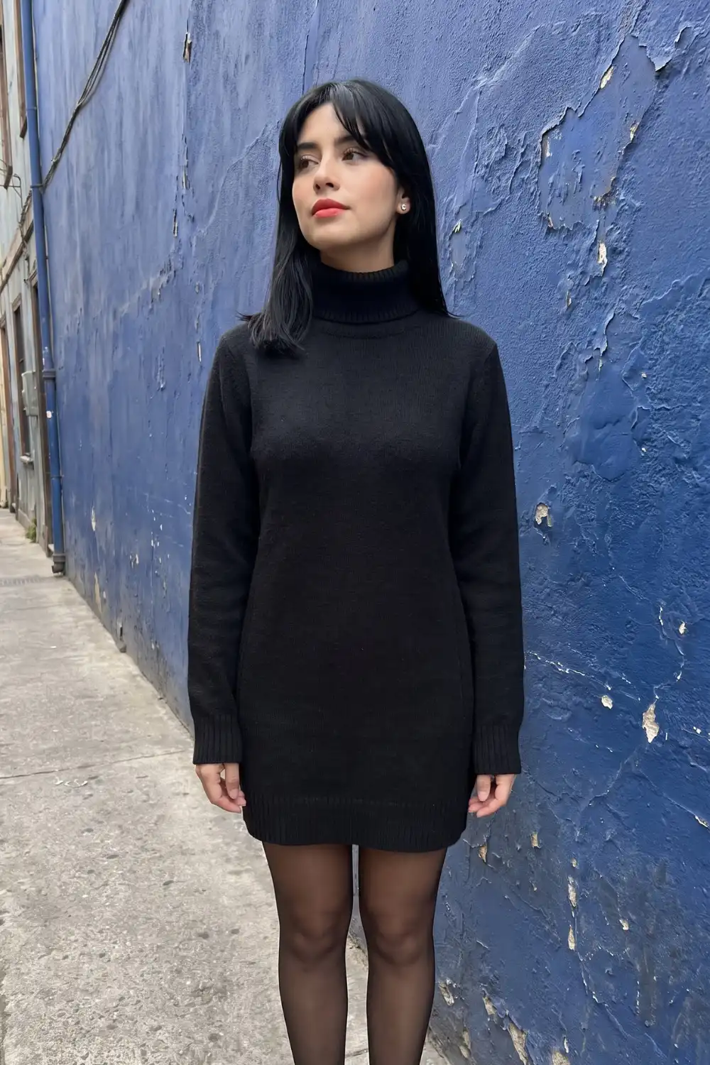 Woman in black knit turtleneck sweater mini dress with black tights