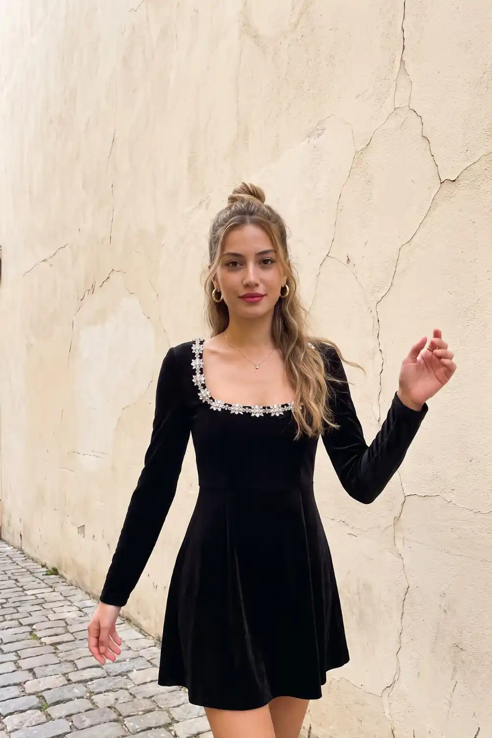 Woman in black velvet long sleeve crystal embellished square neck mini dress