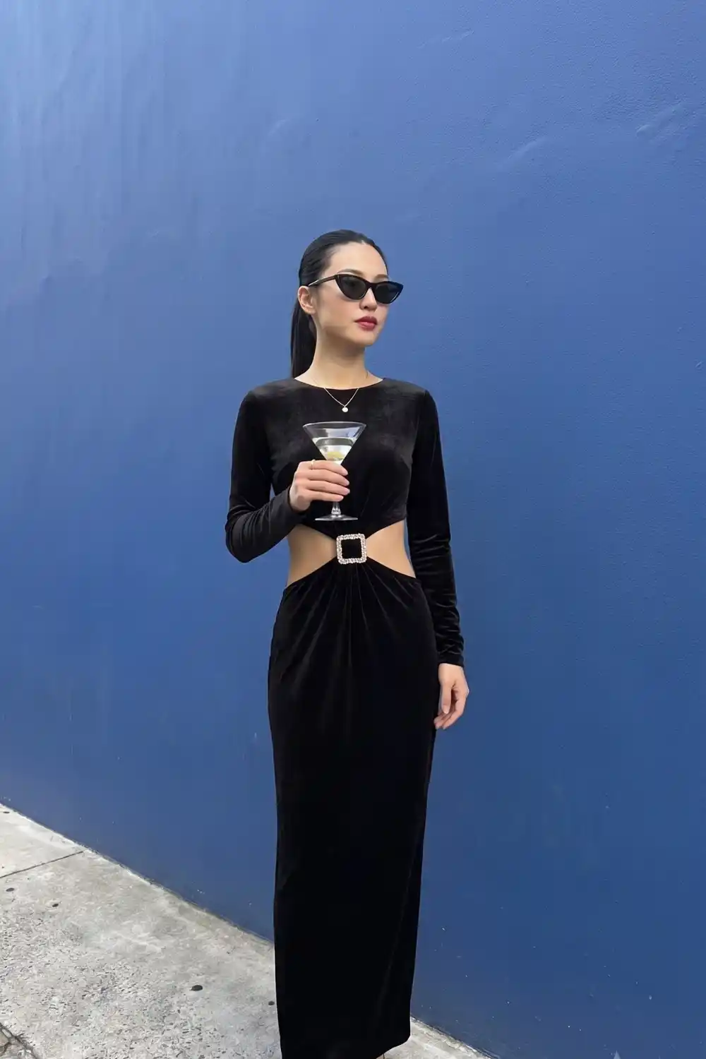 Woman in black velvet long sleeve cutout buckle maxi dress