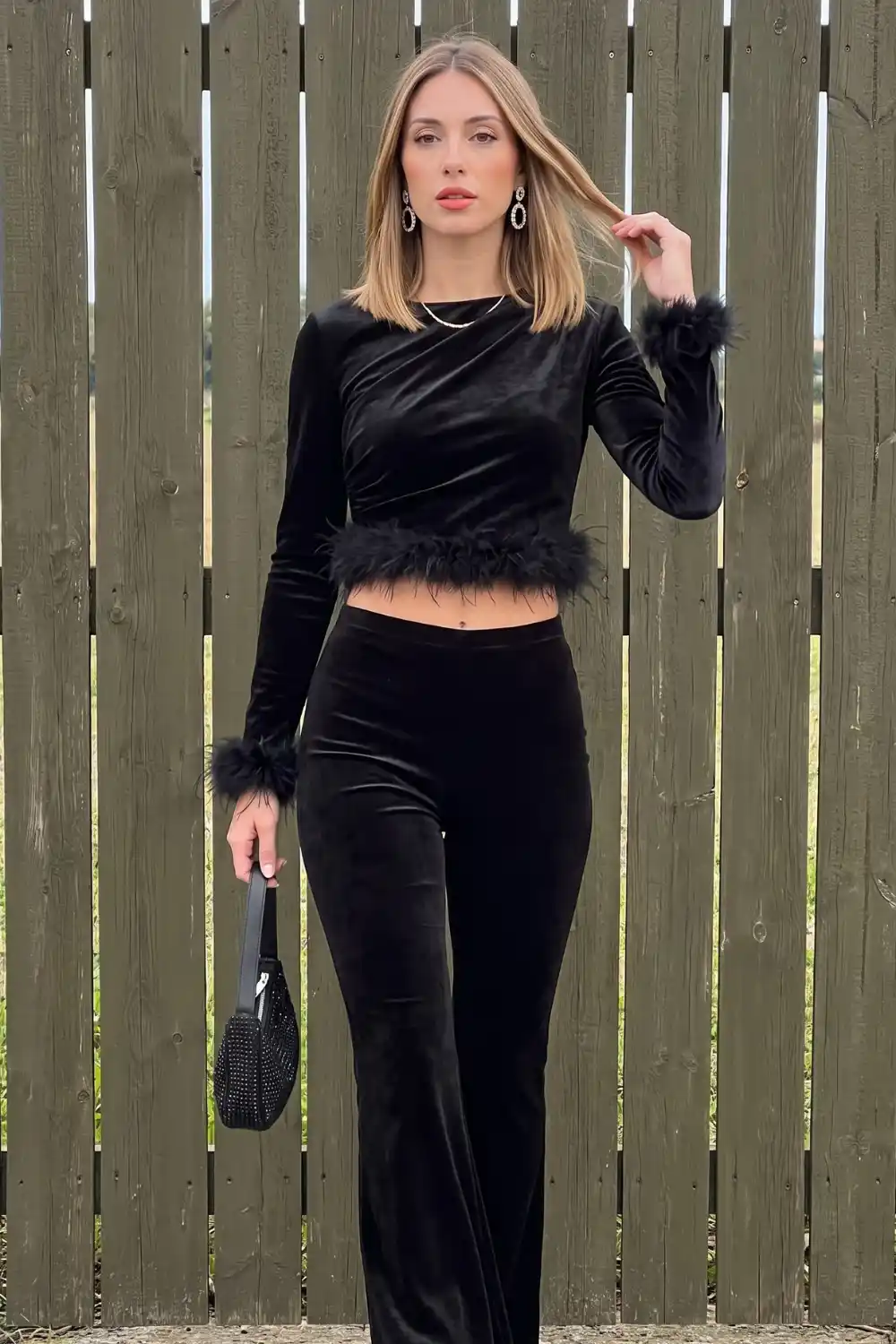 Woman in black velvet feather trim crop top and flare trousers