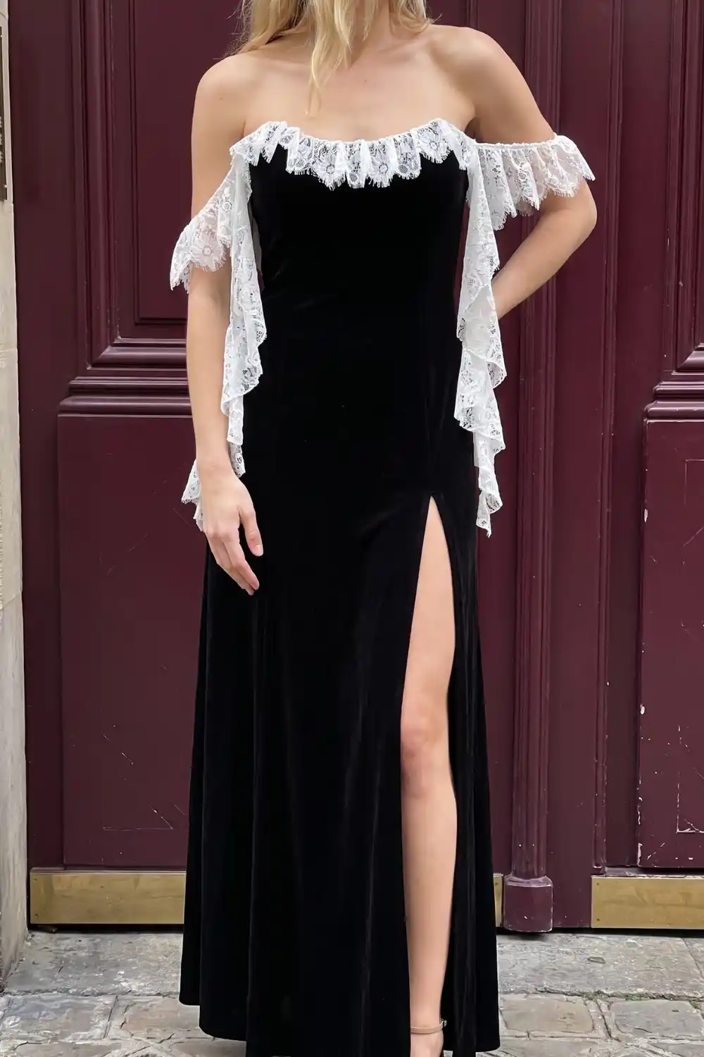 Woman wearing black velvet off shoulder white lace trim side slit maxi dress