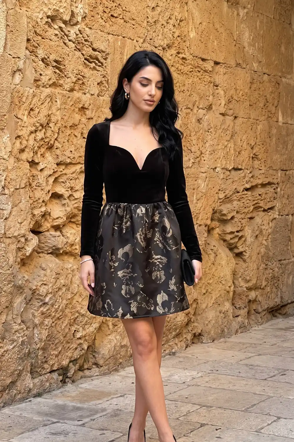 Woman in black velvet sweetheart long sleeve dress with gold floral jacquard bubble skirt