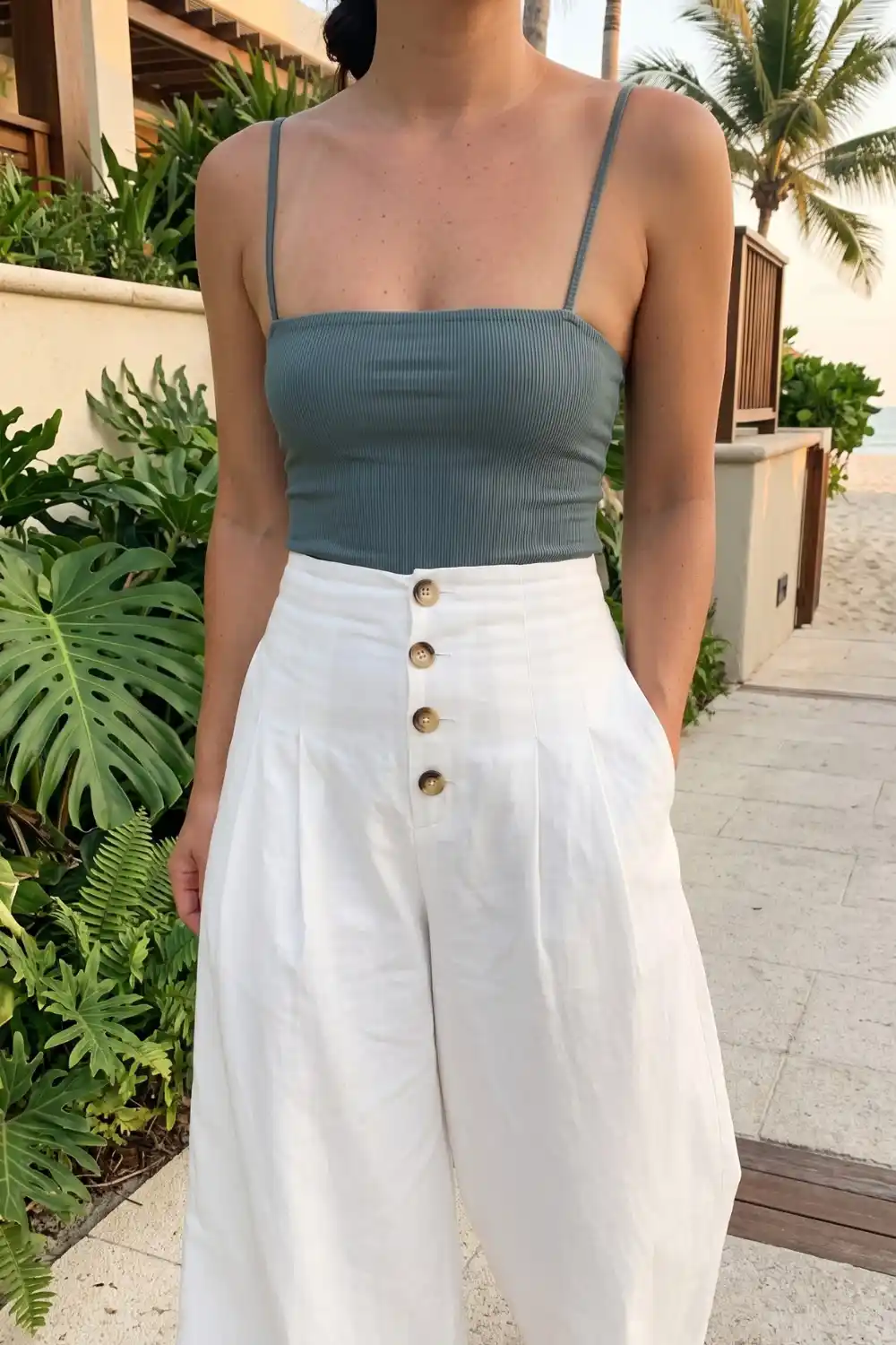 Woman wearing dusty blue ribbed crop top with white high waist button front wide leg linen pants