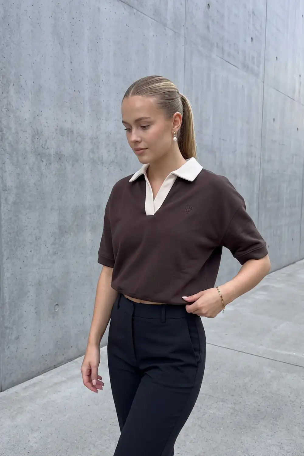 Woman in chocolate brown cropped polo top with black tailored trousers