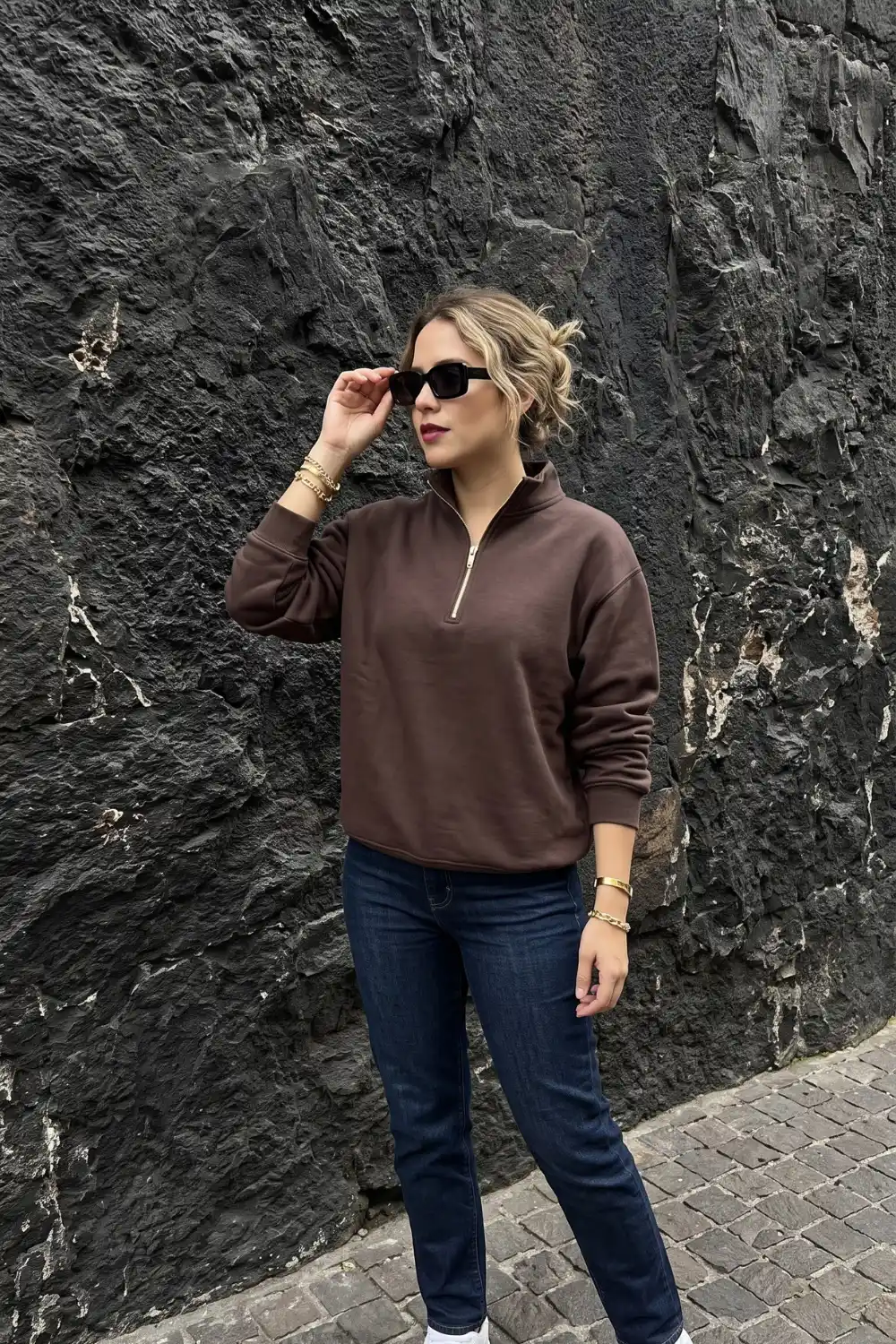 Woman wearing dark brown half-zip sweatshirt with dark wash jeans