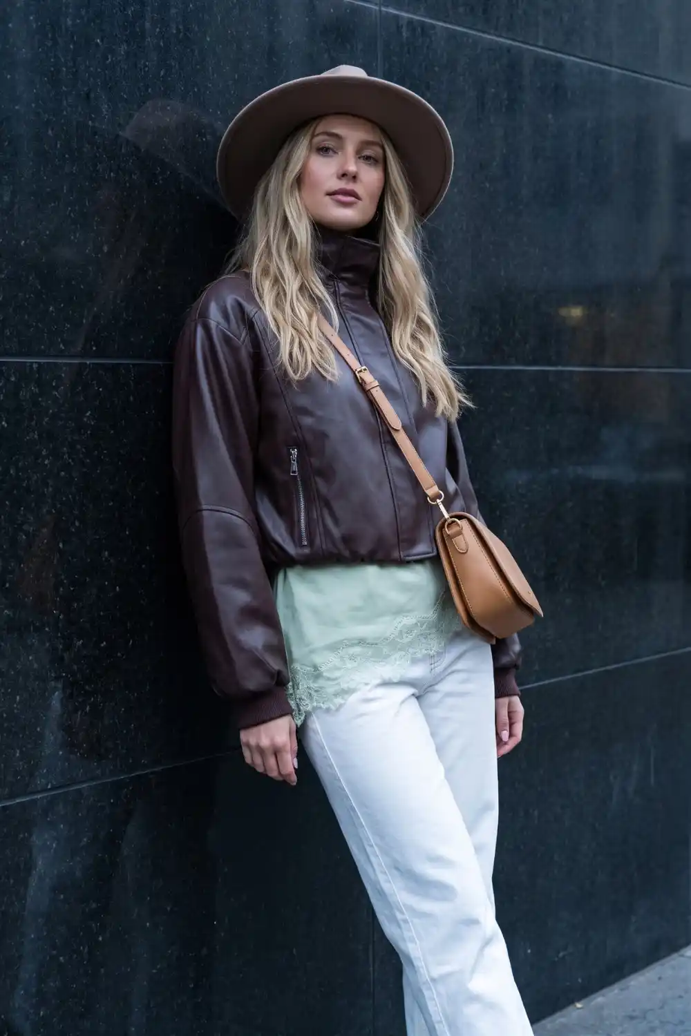 Woman wearing chocolate brown leather bomber jacket with mint lace top white wide leg jeans