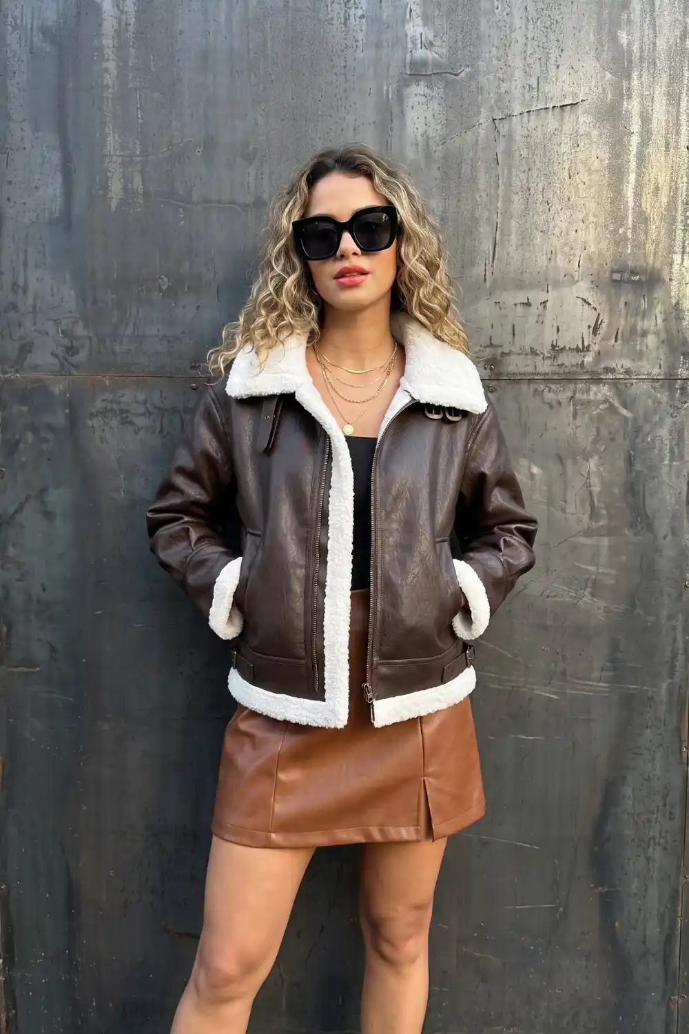 Woman wearing dark brown shearling trim aviator leather jacket with black top
