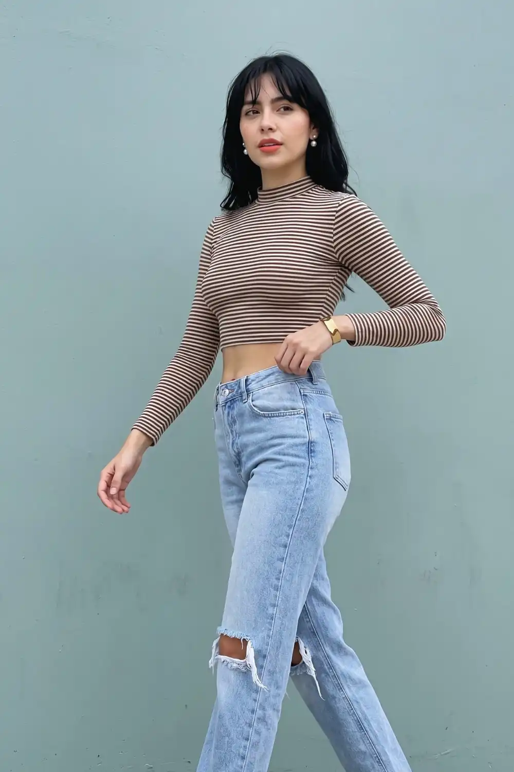 Woman in brown cream stripe cropped mock neck long sleeve top with light wash ripped straight jeans