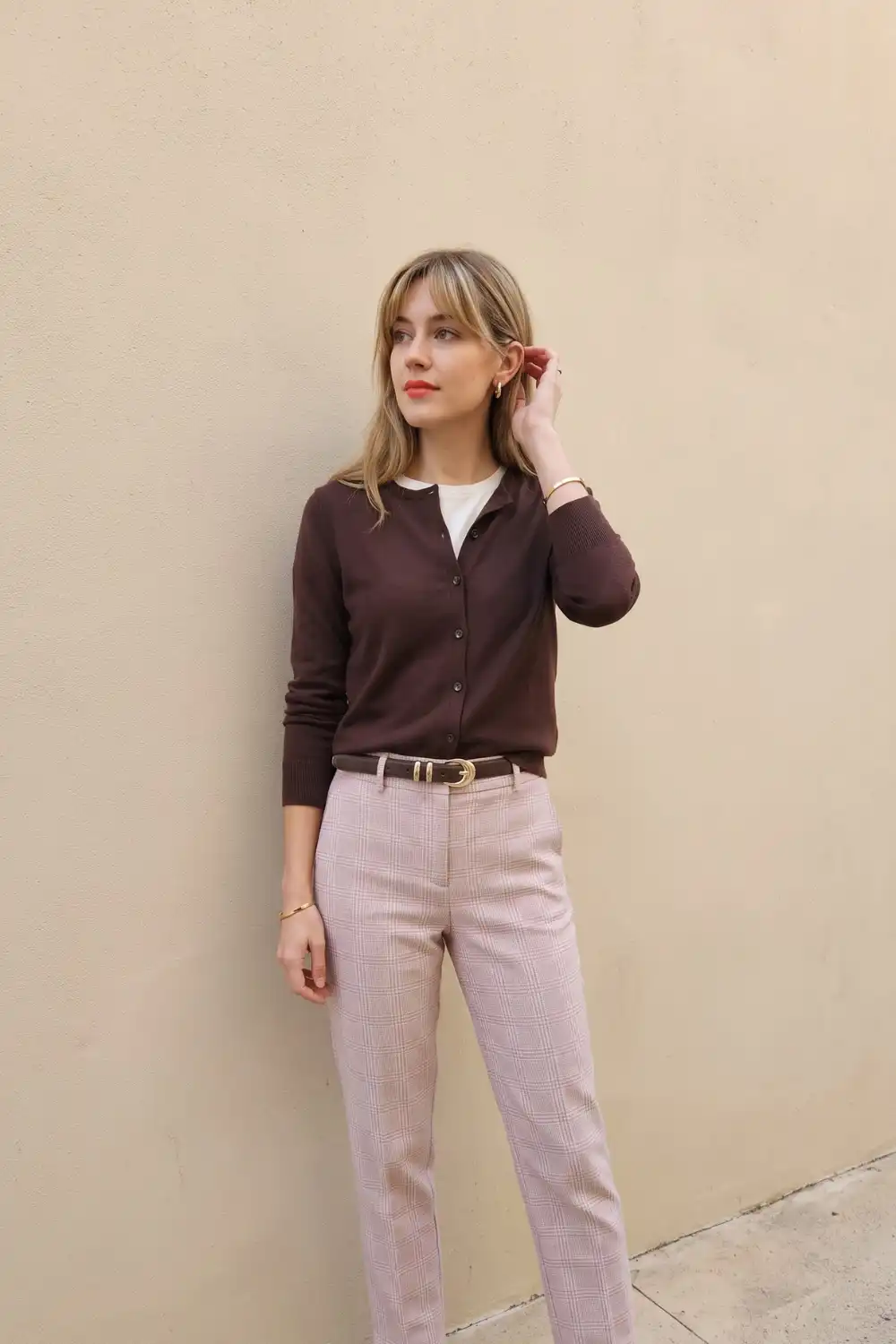 Woman in dark burgundy button cardigan with white tee and pink plaid straight trousers