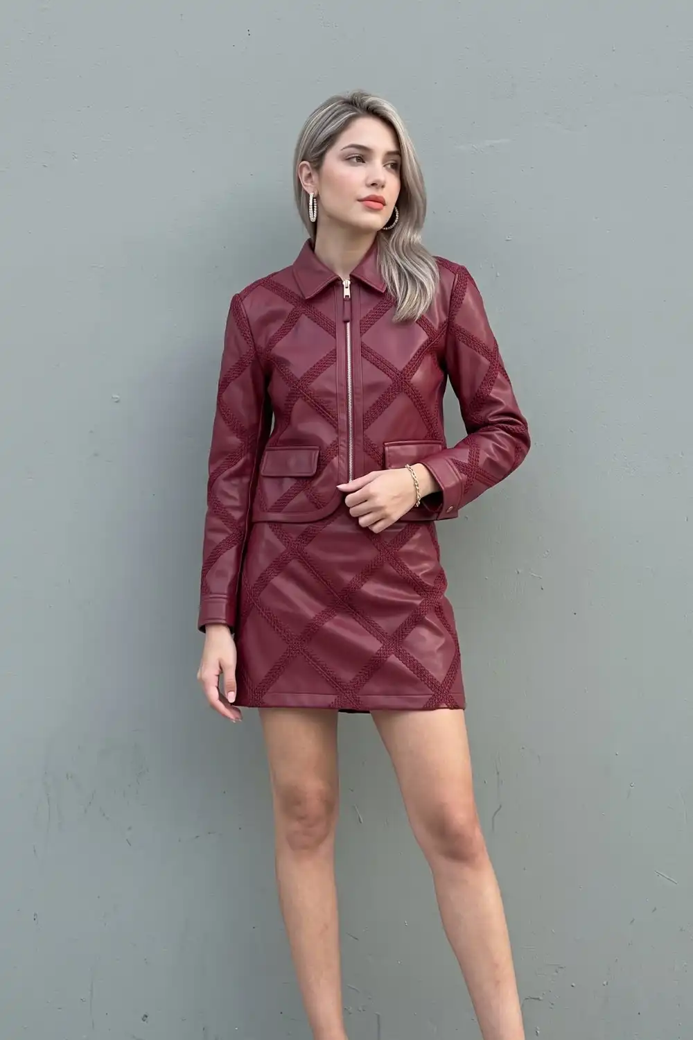 Woman in burgundy quilted leather jacket and mini skirt co-ord set