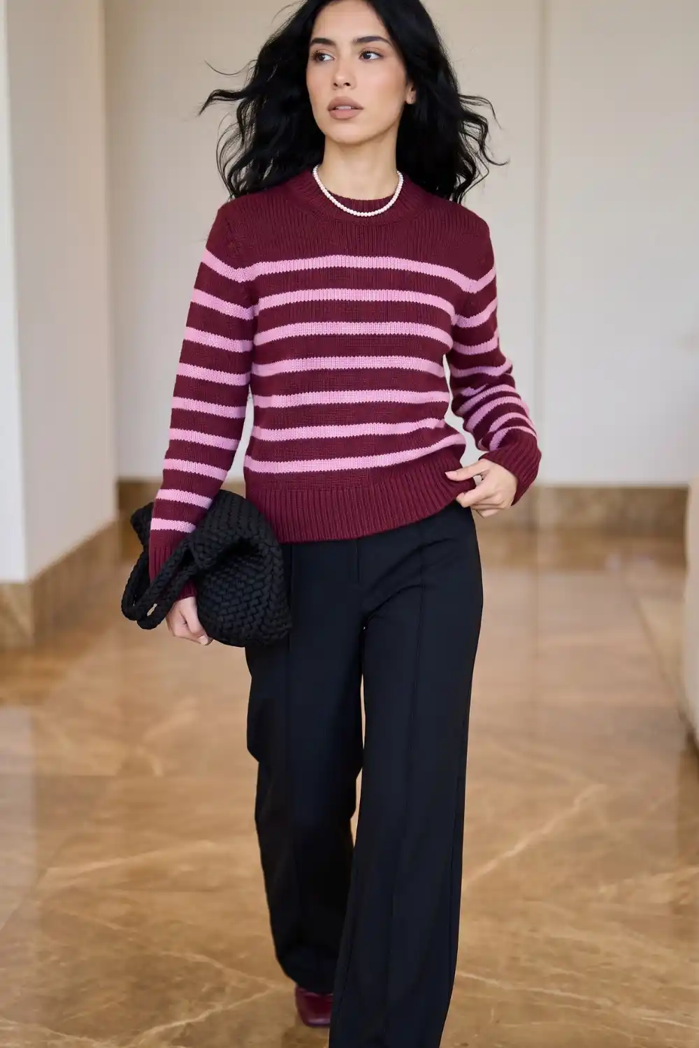 Woman wearing burgundy and pink stripe knit sweater with black wide leg trousers
