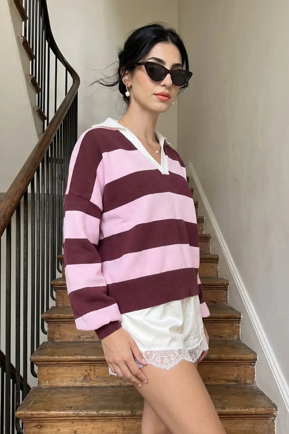 Woman in burgundy pink stripe oversized polo knit sweater with white lace trim shorts