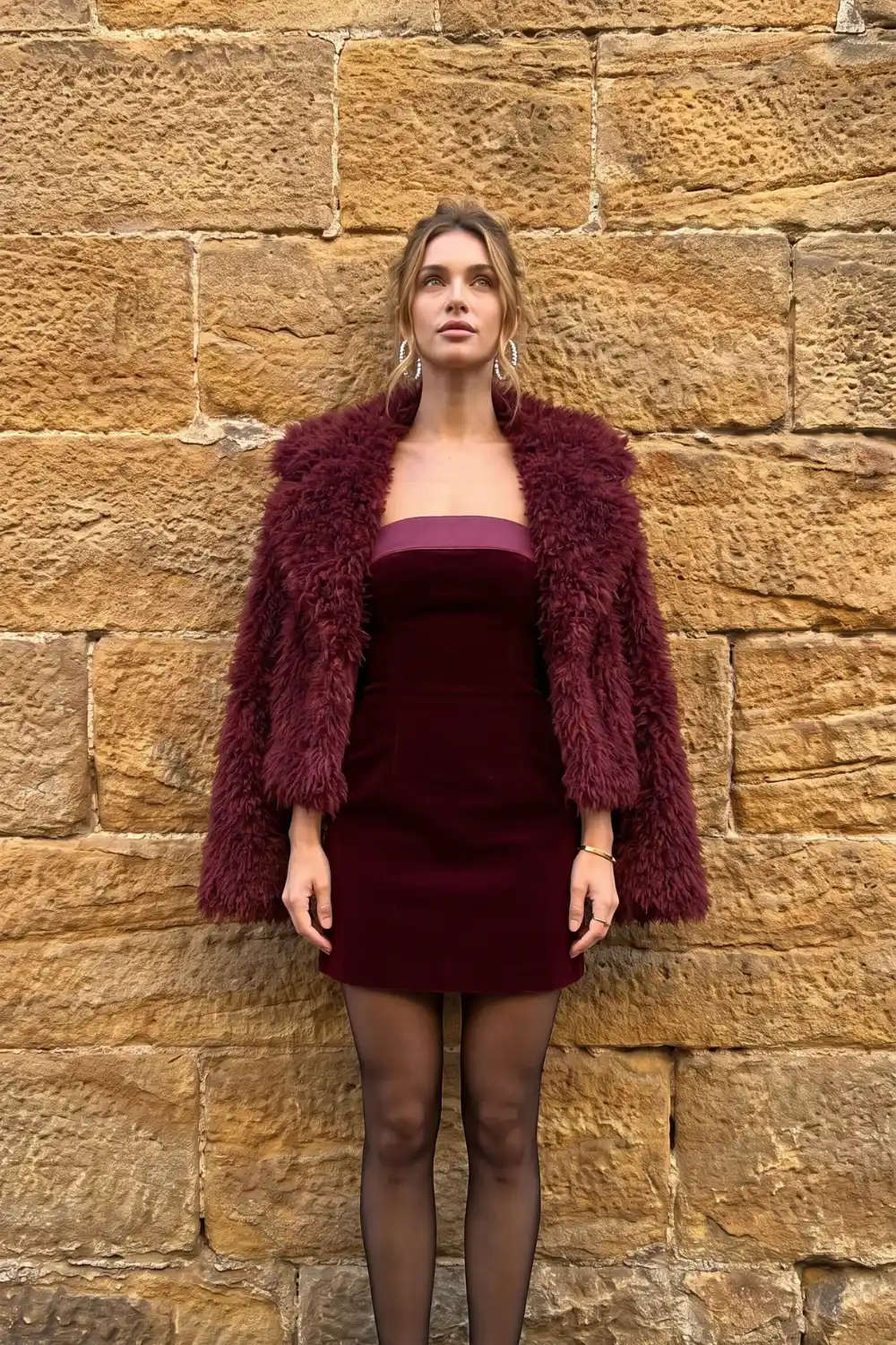 Woman in burgundy velvet strapless mini dress with faux fur cropped jacket