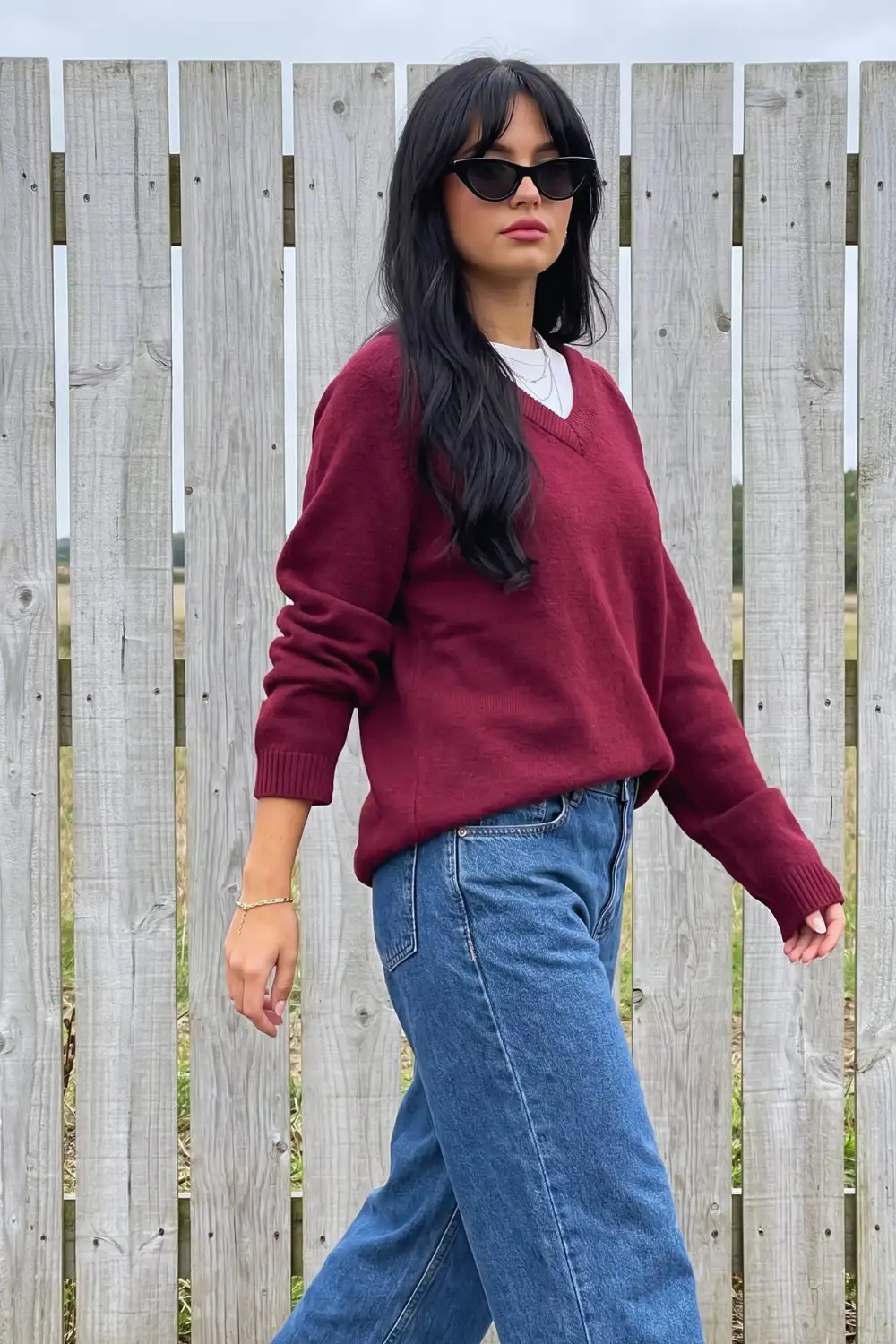 Woman in burgundy oversized v neck sweater over white tee with wide leg jeans