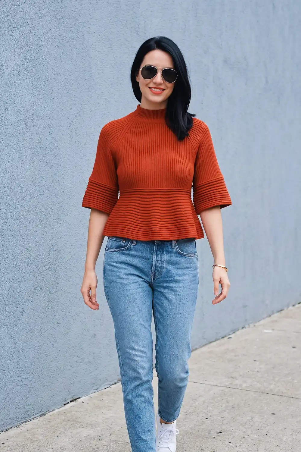 Woman in burnt orange ribbed mock neck peplum short sleeve knit top with light wash mom jeans