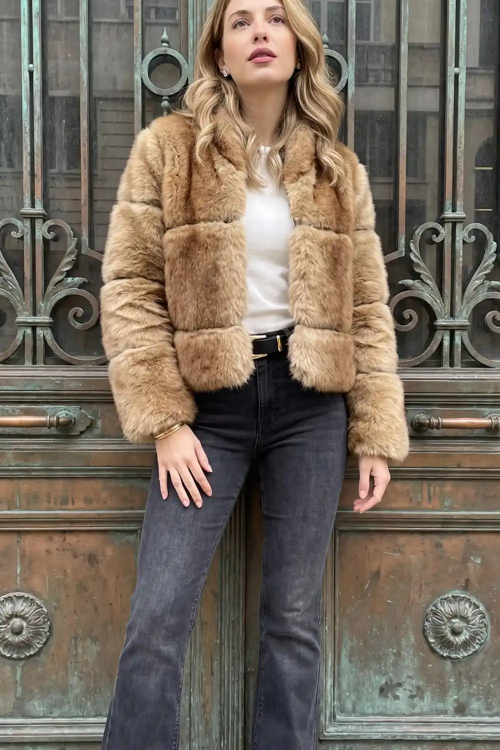 Woman wearing camel faux fur cropped jacket with white tee and dark grey flare jeans