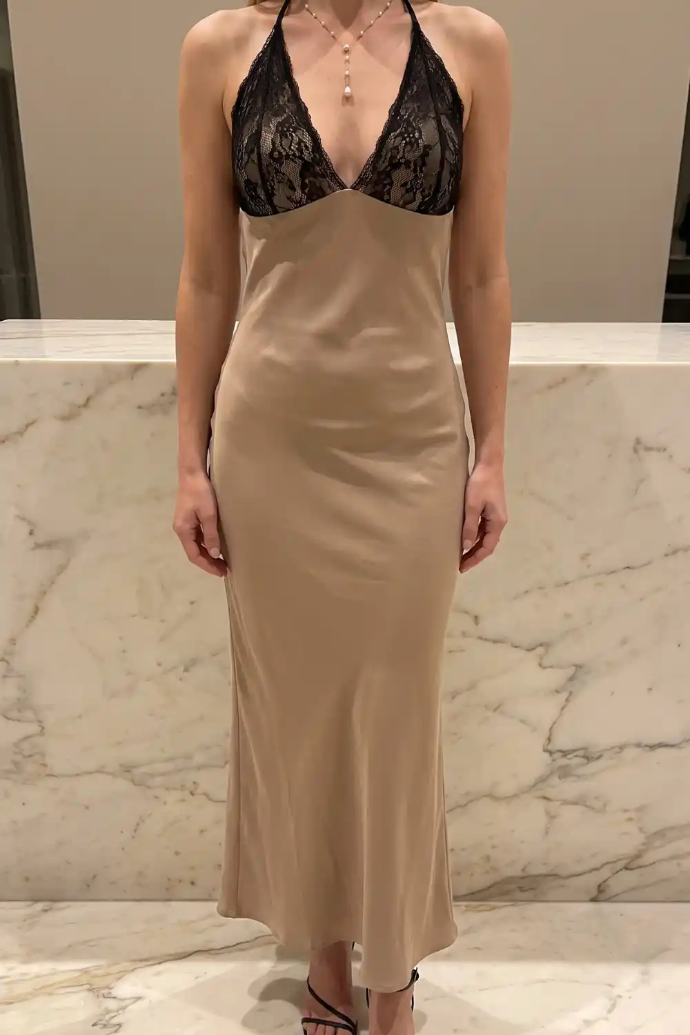 Woman wearing champagne satin slip maxi dress with black lace halter bodice