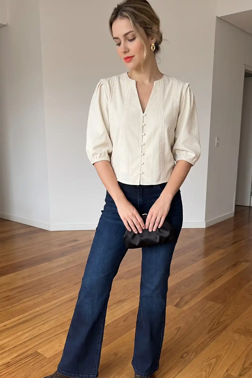Woman wearing cream embroidered puff sleeve blouse with dark wash flare jeans