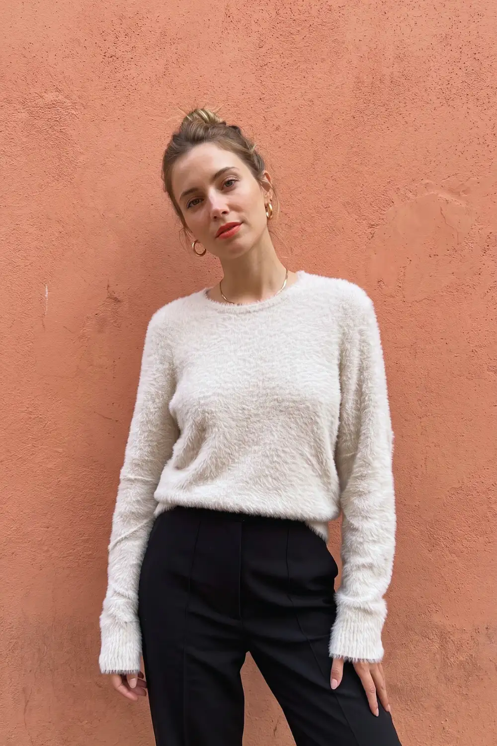 Woman in cream fluffy eyelash knit oversized sweater with black tailored trousers