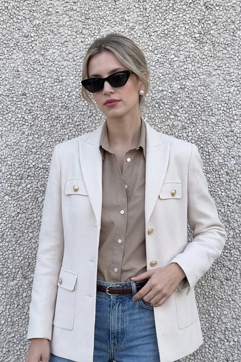 Woman in cream gold button blazer with camel shirt and light wash jeans