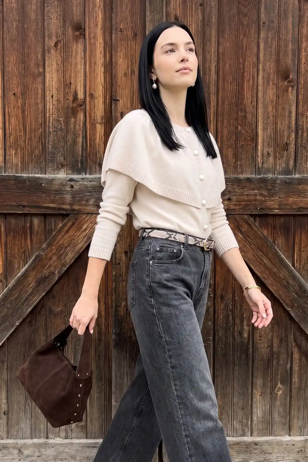 Woman wearing cream pearl button cardigan with grey wide leg jeans and snake print belt