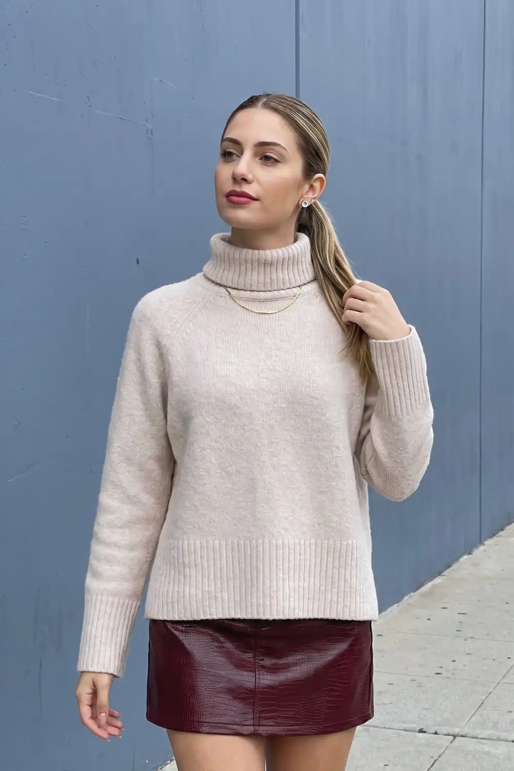Woman in cream oversized turtleneck sweater with burgundy croc leather mini skirt