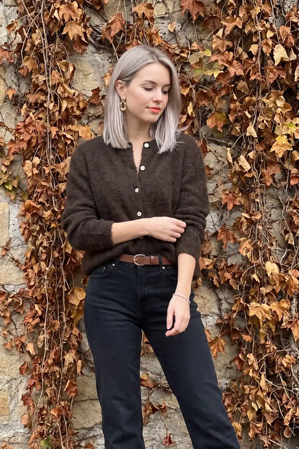 Woman wearing dark brown fluffy button cardigan with black straight jeans and tan leather belt