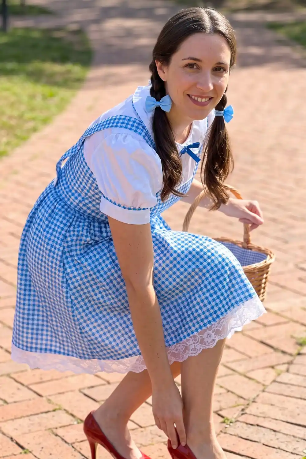 Woman dressed as Dorothy from Wizard of Oz in blue gingham dress with red heels and wicker basket