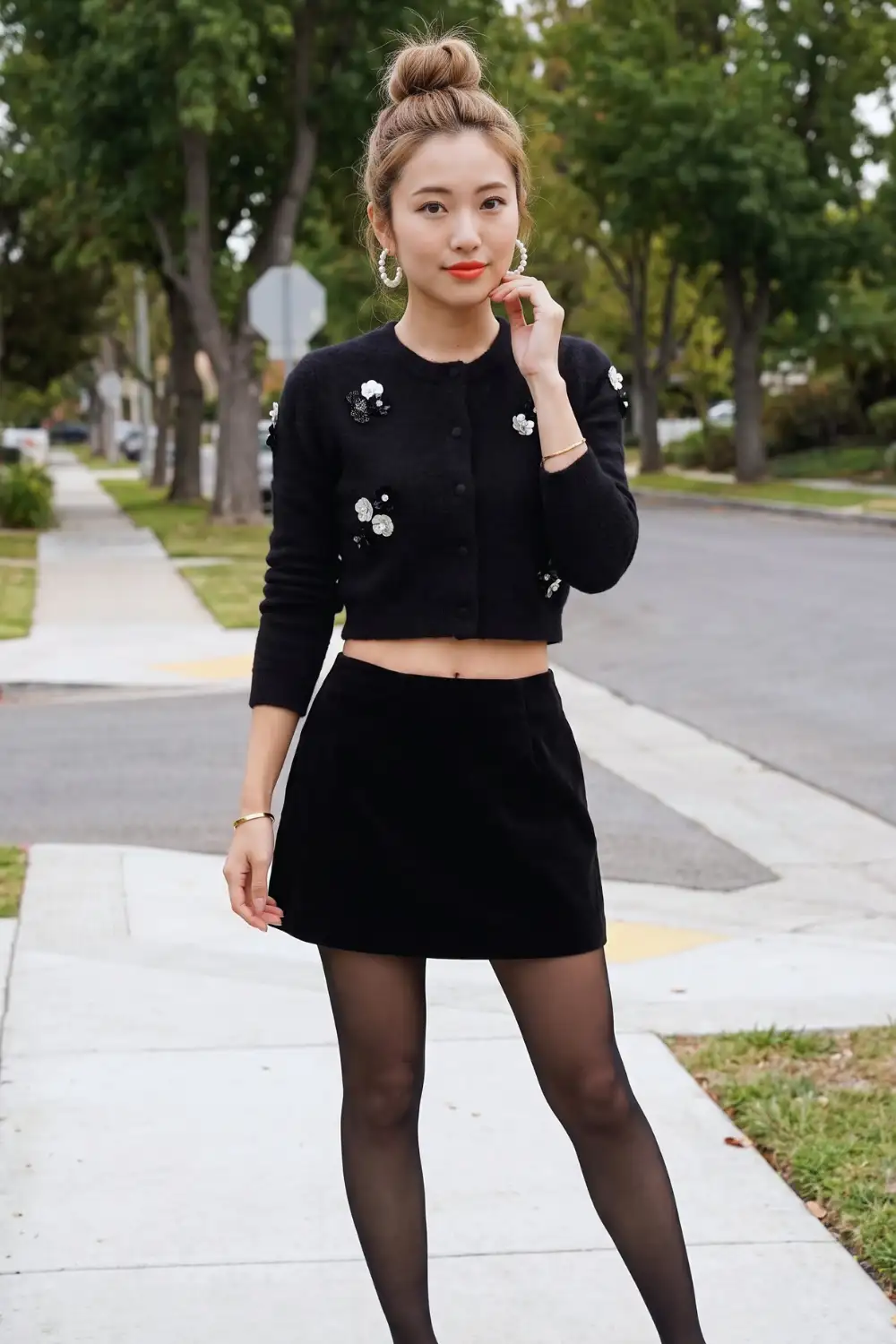Woman in black sequin floral crop cardigan with black velvet mini skirt and sheer tights