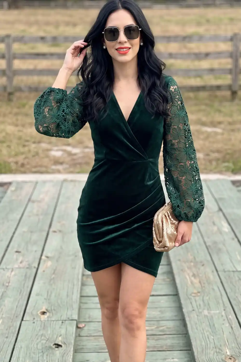 Woman in emerald green velvet wrap mini dress with floral lace puff sleeves